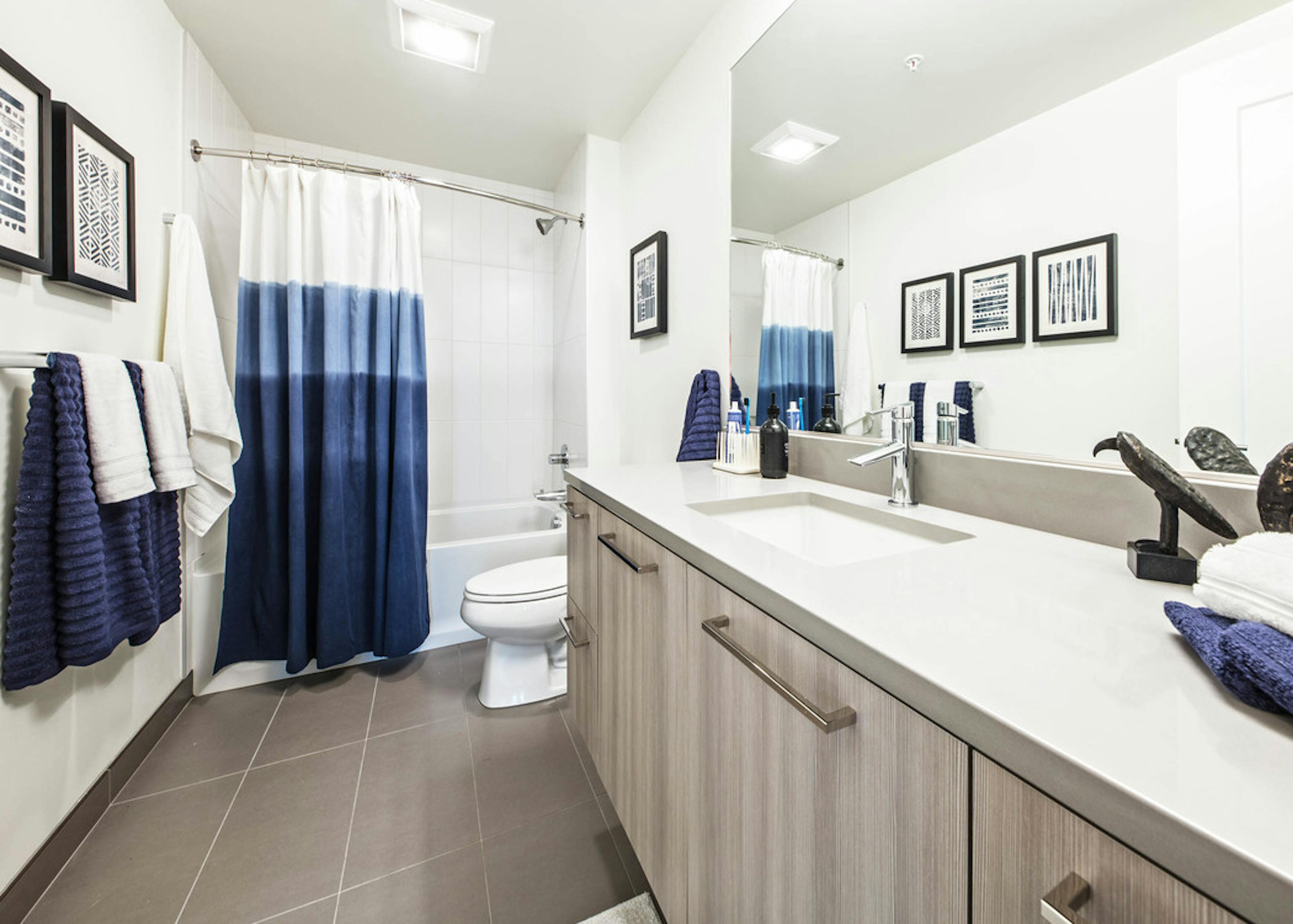 Interior view of AMLI Arc apartment bathroom with toilet shower and tub combination with white quartz counter tops