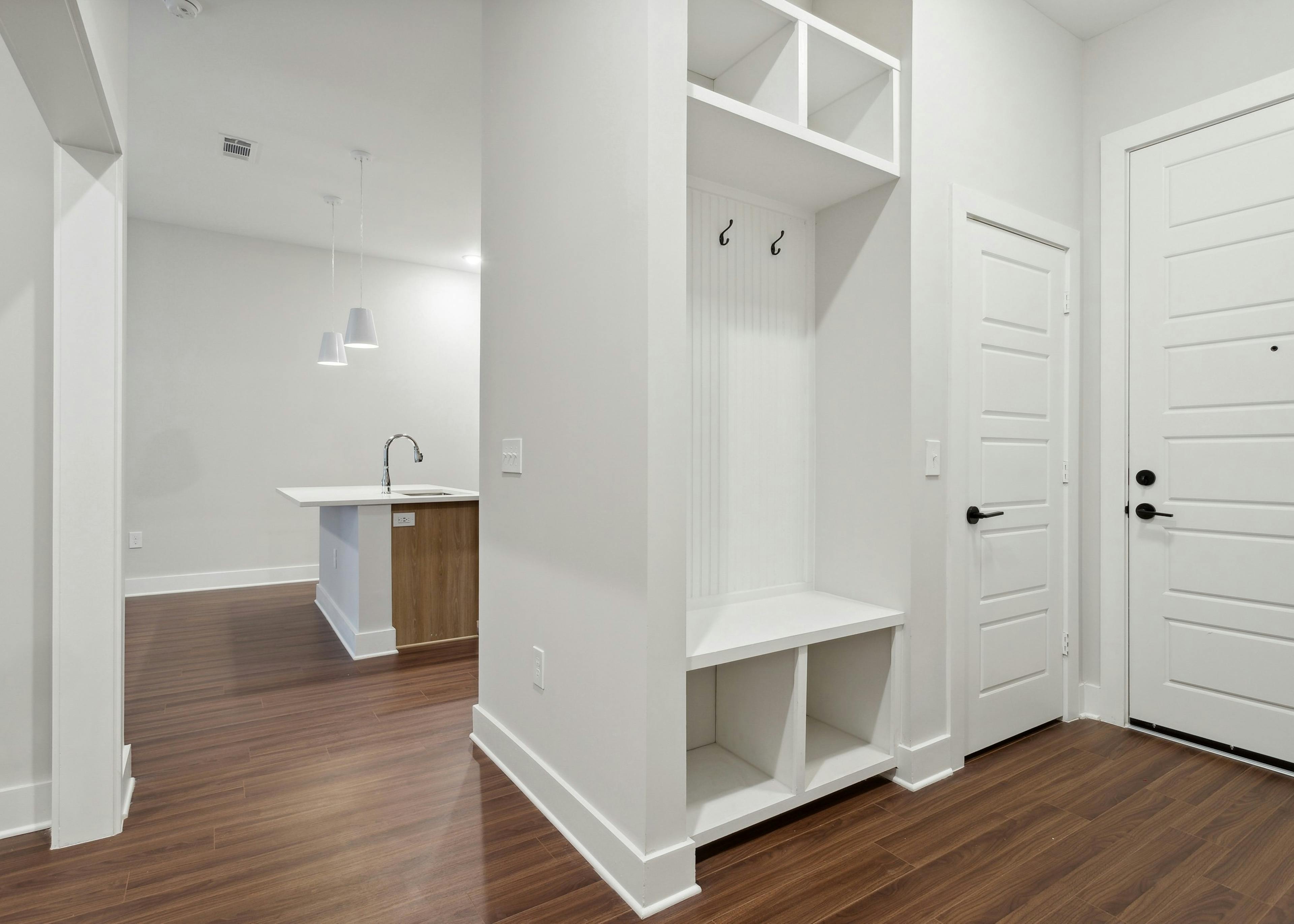 
Mudroom with open closet with white beadboard and shelves and white six-panel doors and view to kitchen at AMLI Flatiron 