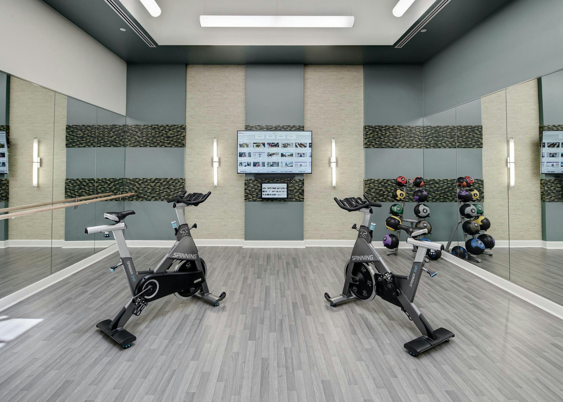 Close up of two exercise machines in an AMLI Evanston amenity space surrounded by mirrored walls with a flat screen TV