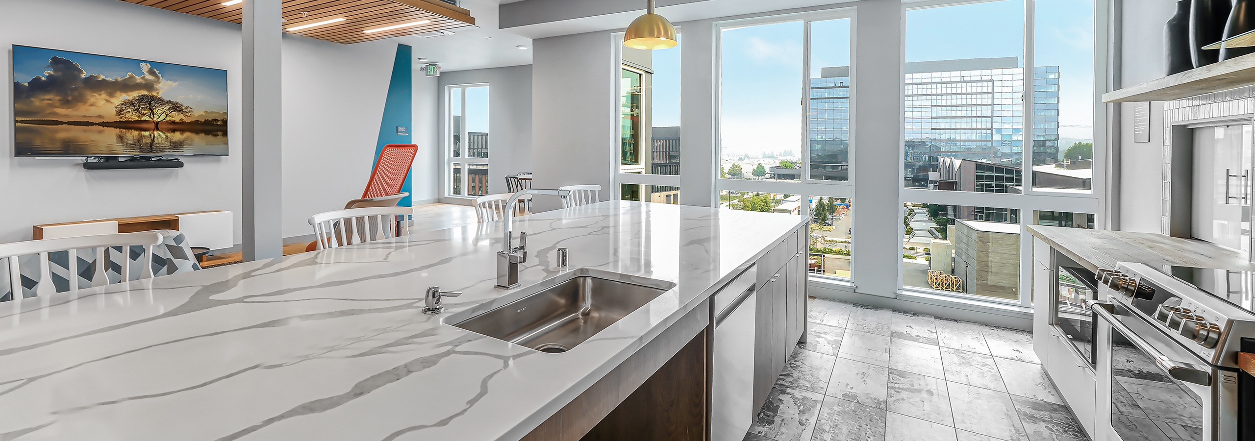 Interior view of AMLI Spring District clubroom kitchen with gray flooring and marble island and floor to ceiling windows