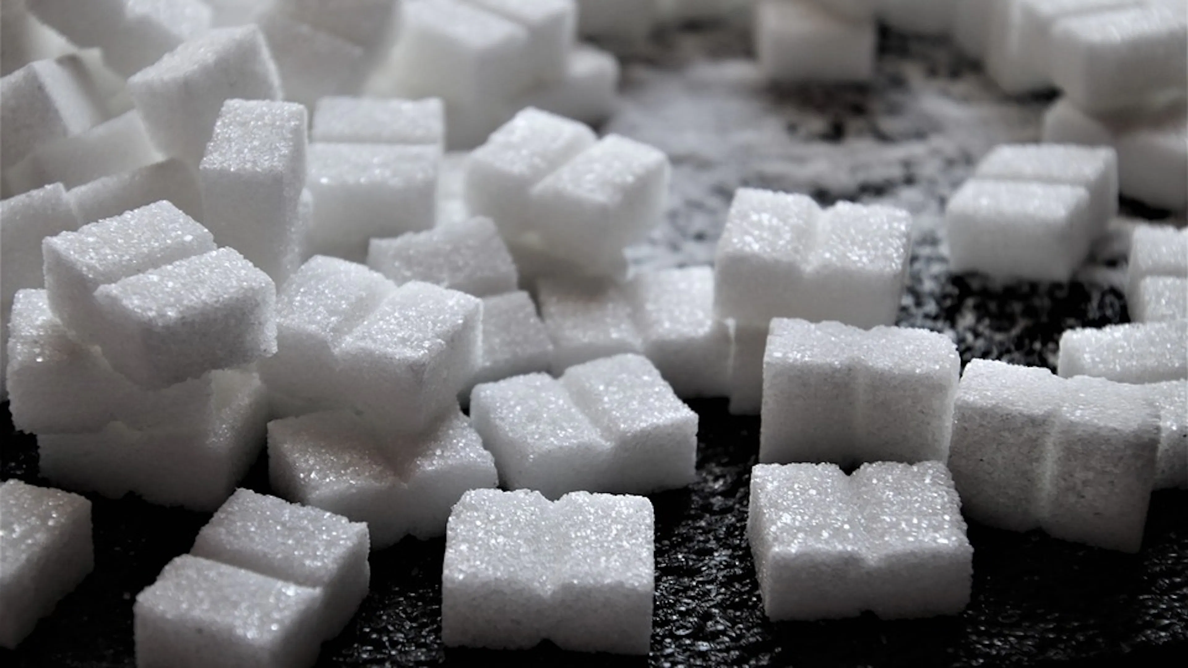 A dark wooden table covered with white sugar cubes filling the entire frame