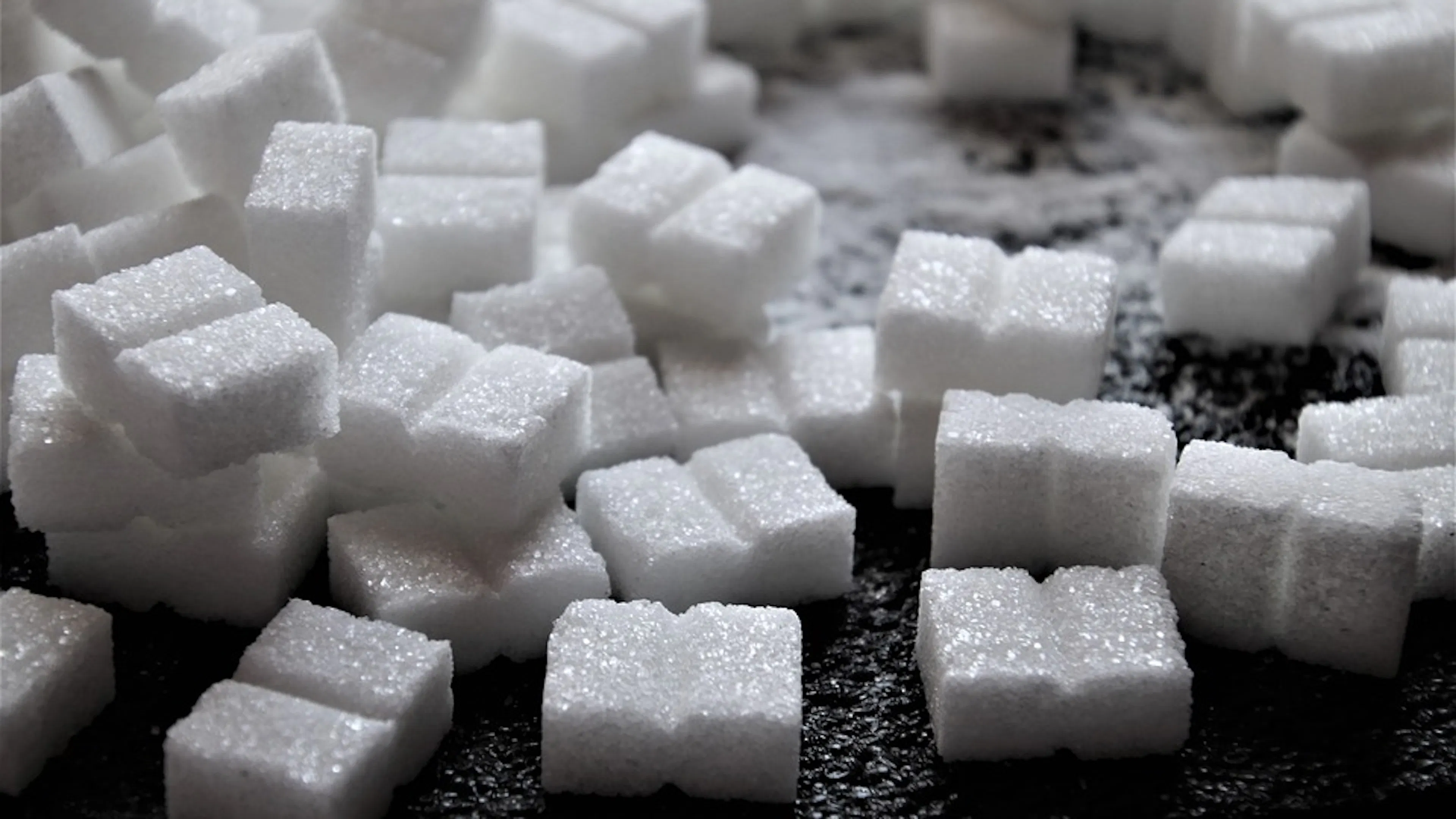A dark wooden table covered with white sugar cubes filling the entire frame