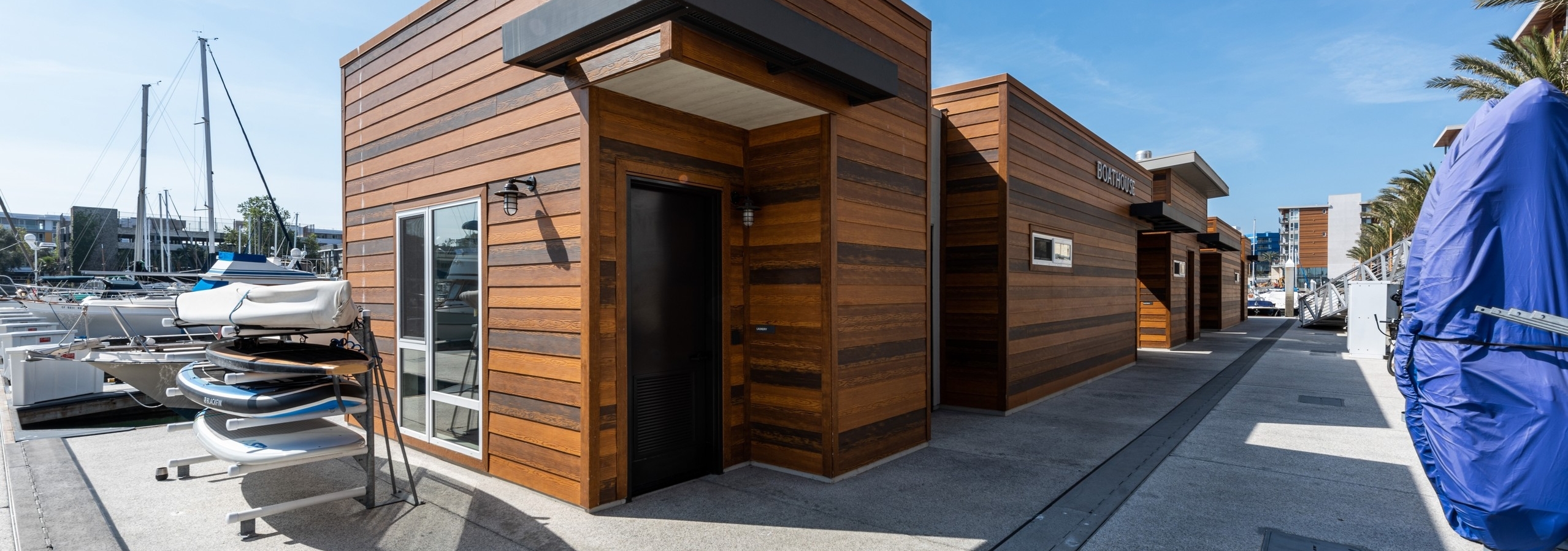 Daytime view of the marina boat house with full wood paneling façade and paddleboard rack at AMLI Marina Del Rey apartments