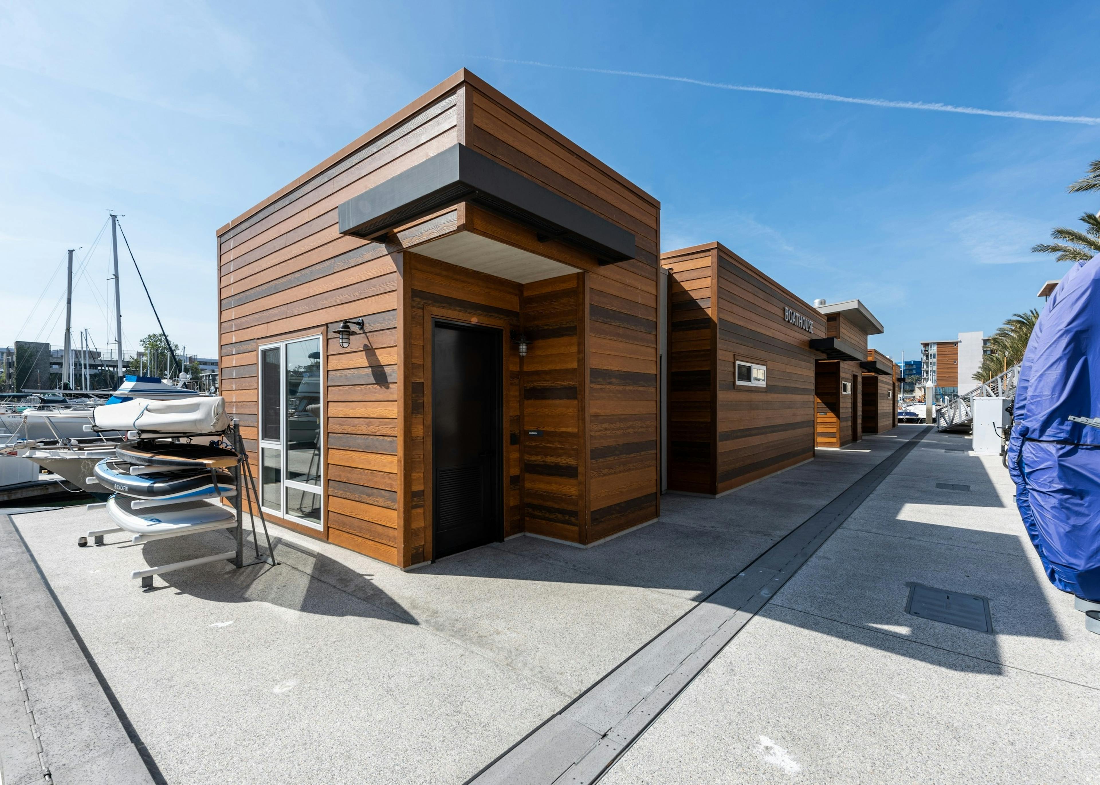 Daytime view of the marina boat house with full wood paneling façade and paddleboard rack at AMLI Marina Del Rey apartments