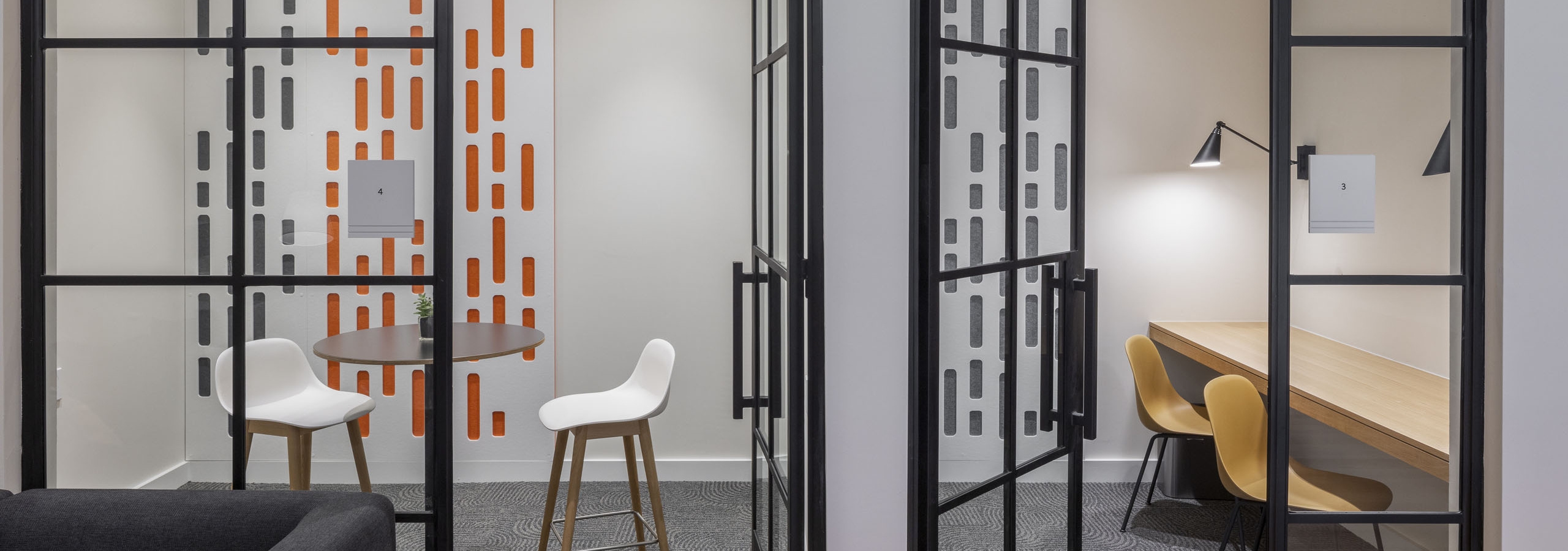 Private working rooms at AMLI Branch Park coworking space with colorful seating and floor to ceiling metal and glass doors