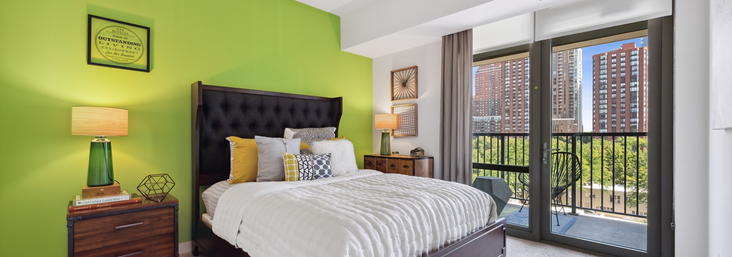 AMLI 900 apartment bedroom with bright green wall and large glass door leading to a balcony with city views