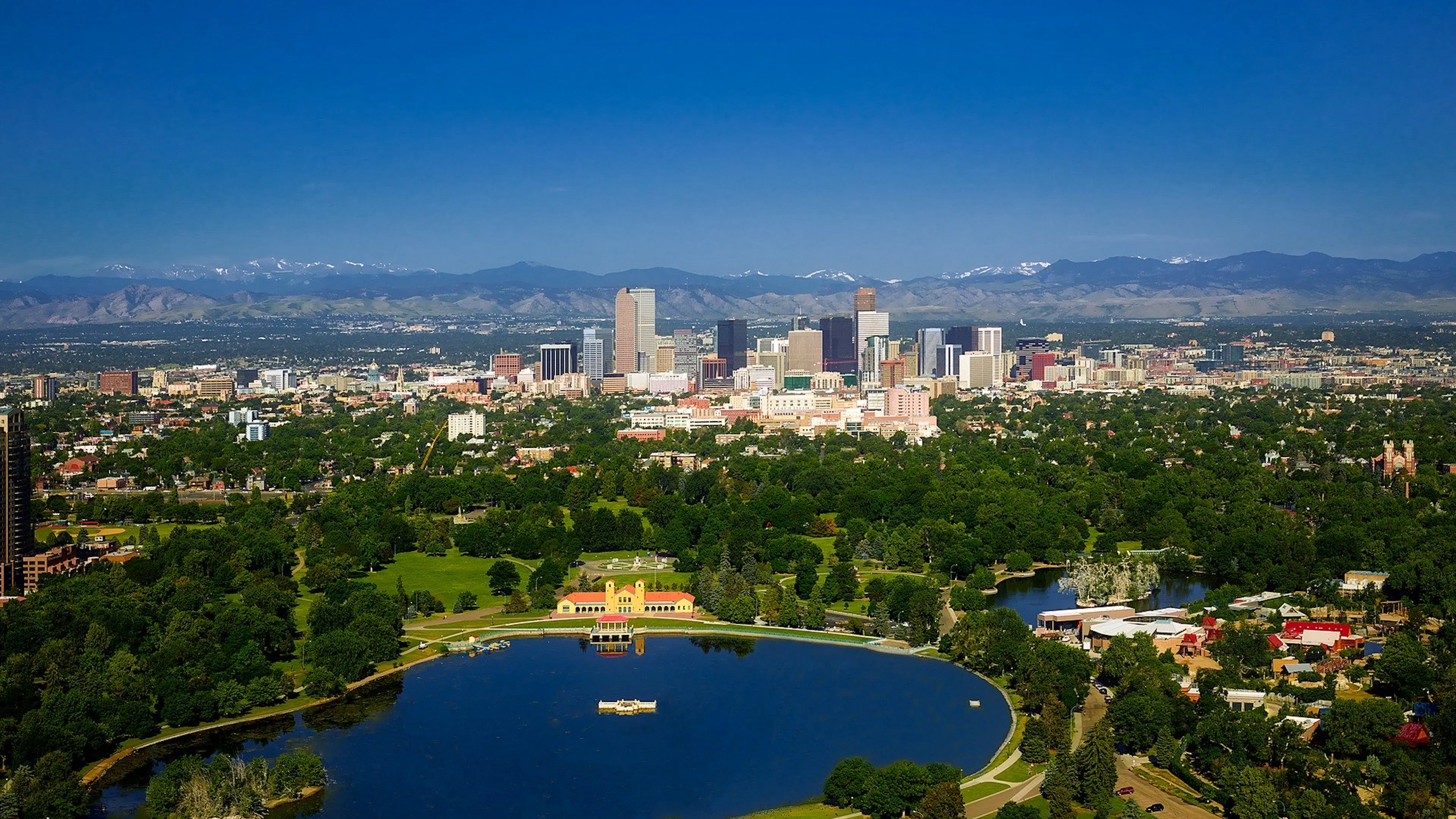 Denver's skyline with a lake in the foreground and the mountains in the background