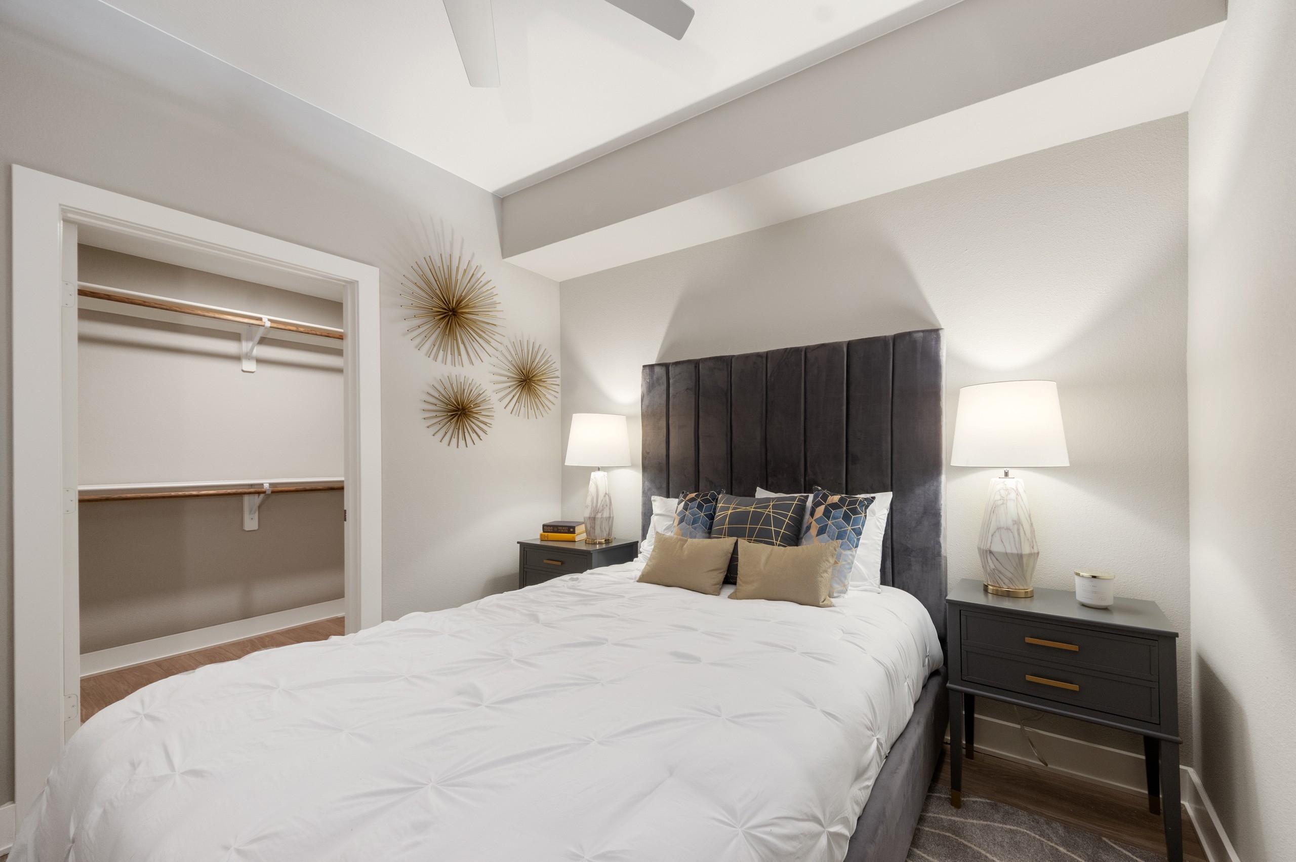 AMLI Riverfront Green apartment bedroom featuring a white bedspread and geometric decor with view into walk in closet