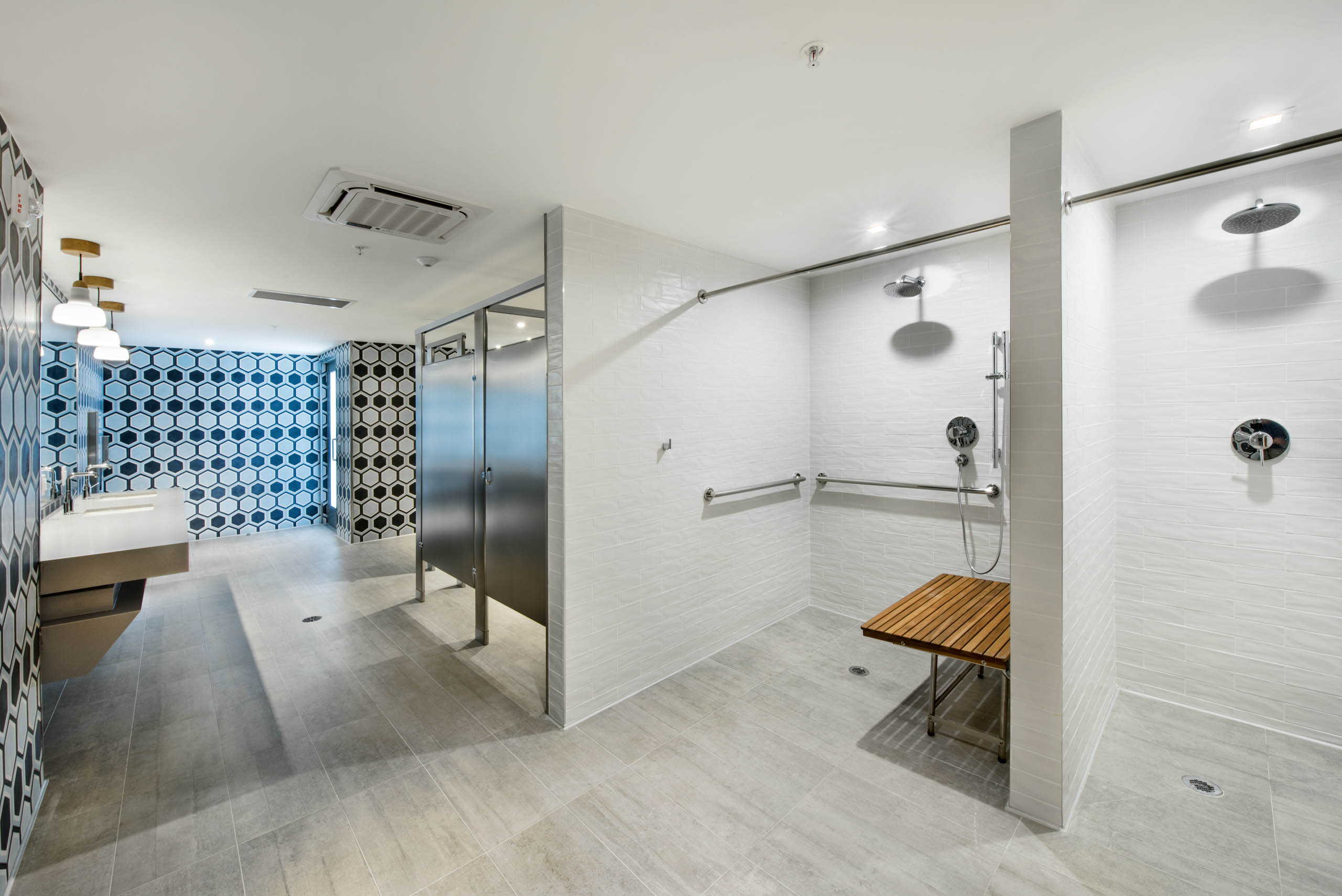 Fitness center showers with white tile and wood slat seat and black and white tile accent wall at AMLI Midtown 29 apartments