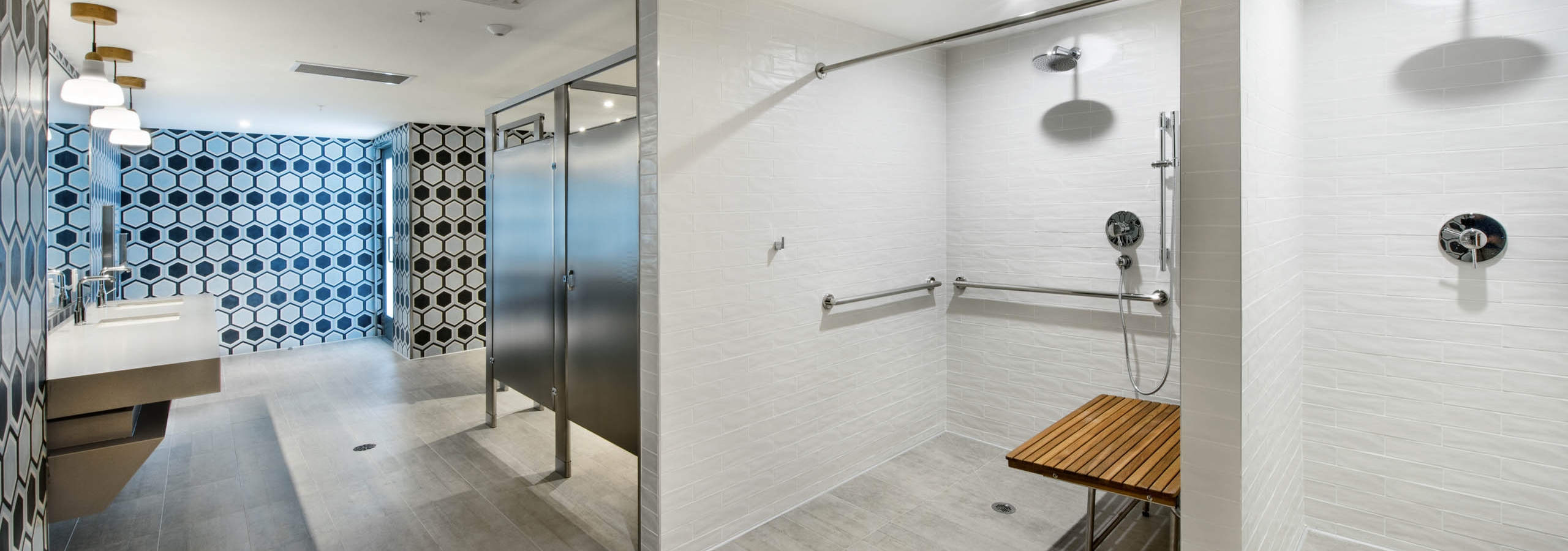 Fitness center showers with white tile and wood slat seat and black and white tile accent wall at AMLI Midtown 29 apartments