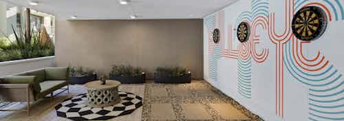 Daytime view of outdoor courtyard cave with round checkered rug and three dartboards on wall at AMLI Park Broadway apartments