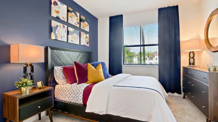 Interior view of AMLI Toscana Place townhome bedroom with bed centered on wall with décor and view from a window
