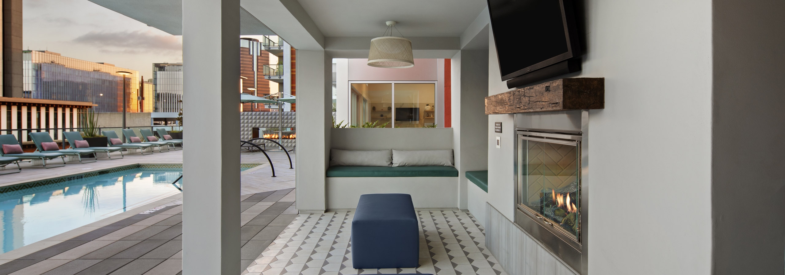 Shaded pool deck area with plush seating and flat screen TV above fireplace overlooking the pool at AMLI Park Broadway