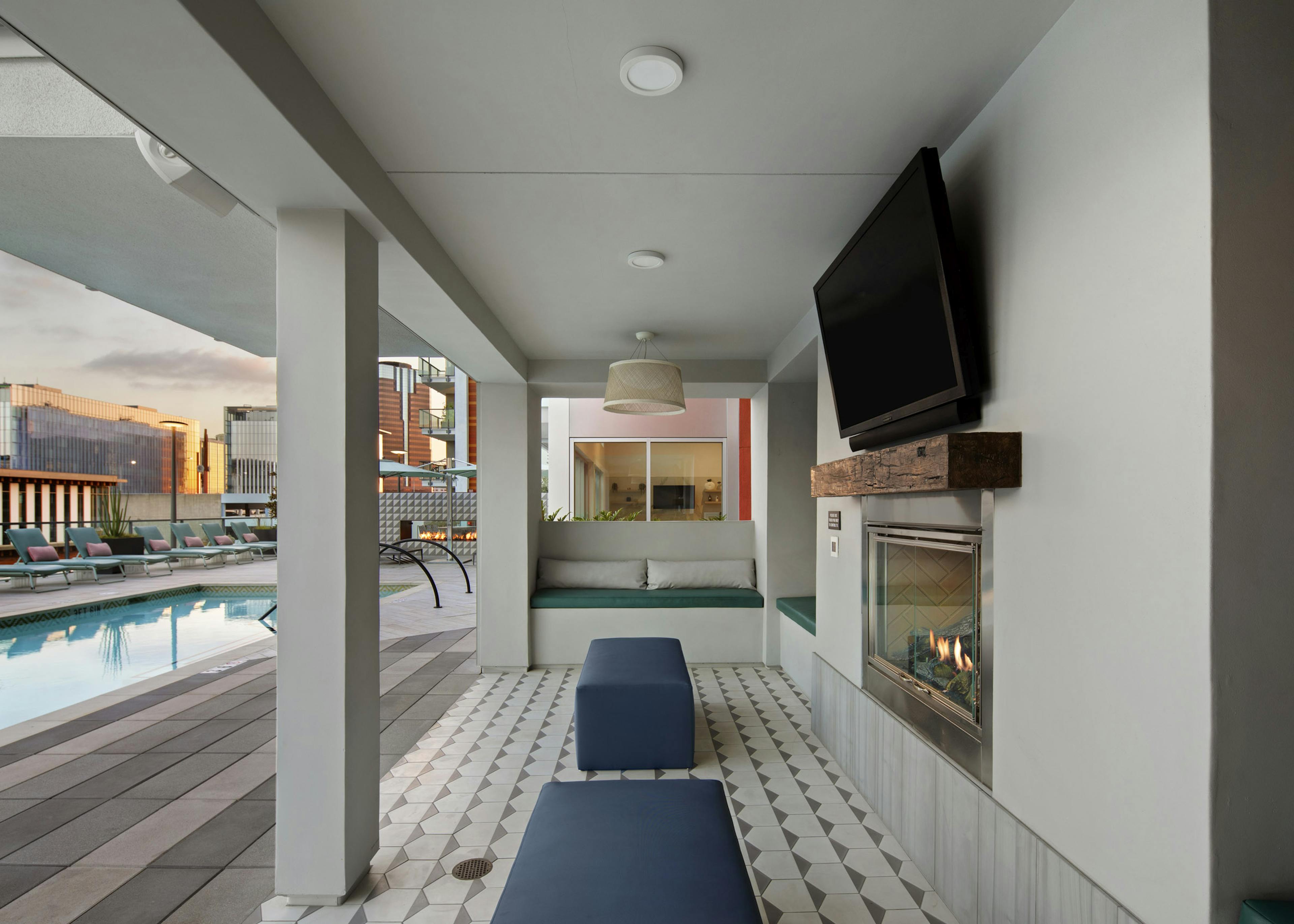 Shaded pool deck area with plush seating and flat screen TV above fireplace overlooking the pool at AMLI Park Broadway 