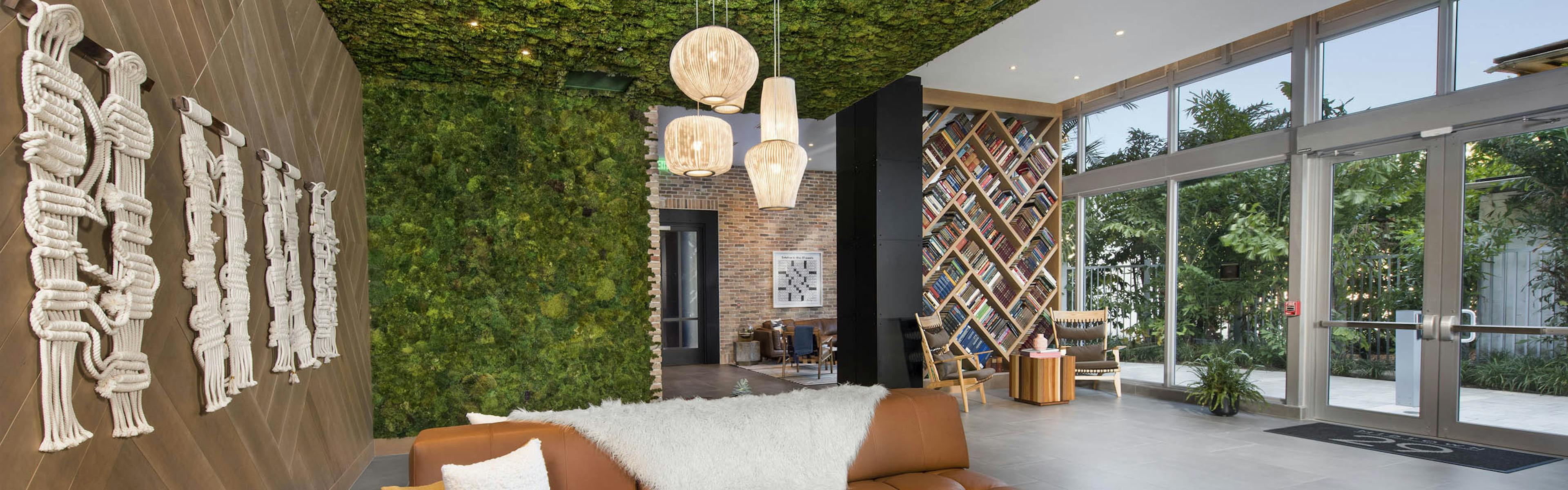 AMLI Midtown 29 clubhouse with green living wall and ceiling with wood wall and leather couch and book accent divider wall