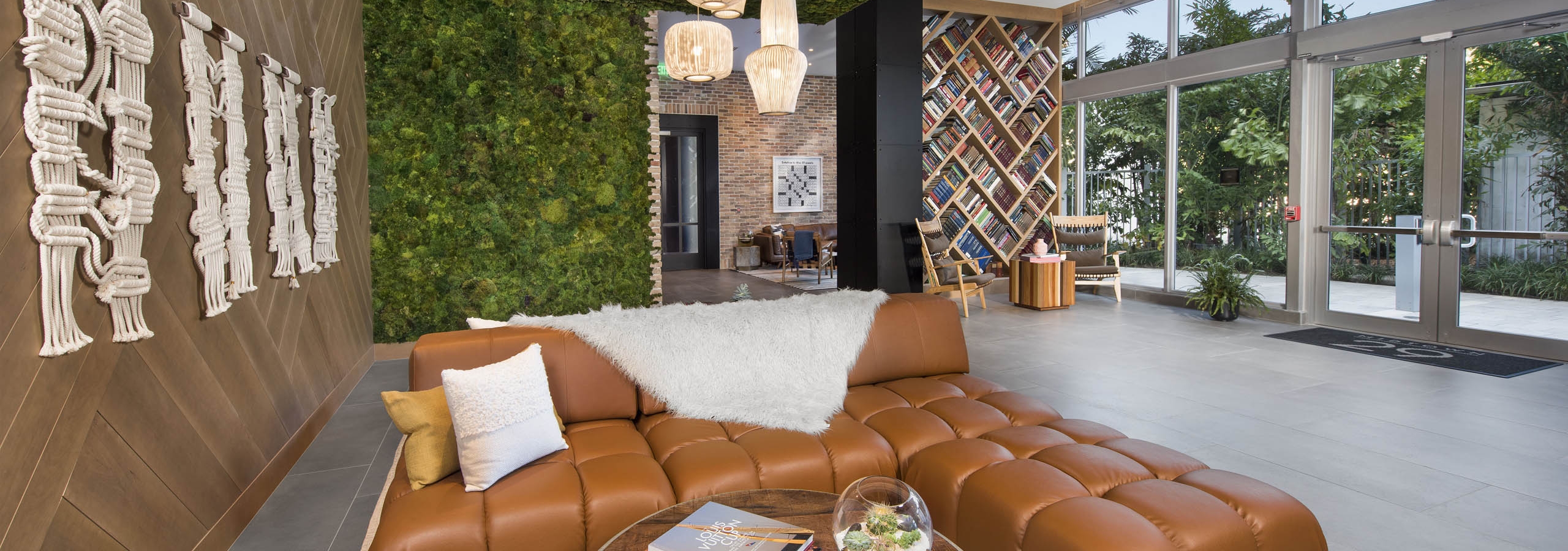 AMLI Midtown 29 clubhouse with green living wall and ceiling with wood wall and leather couch and book accent divider wall