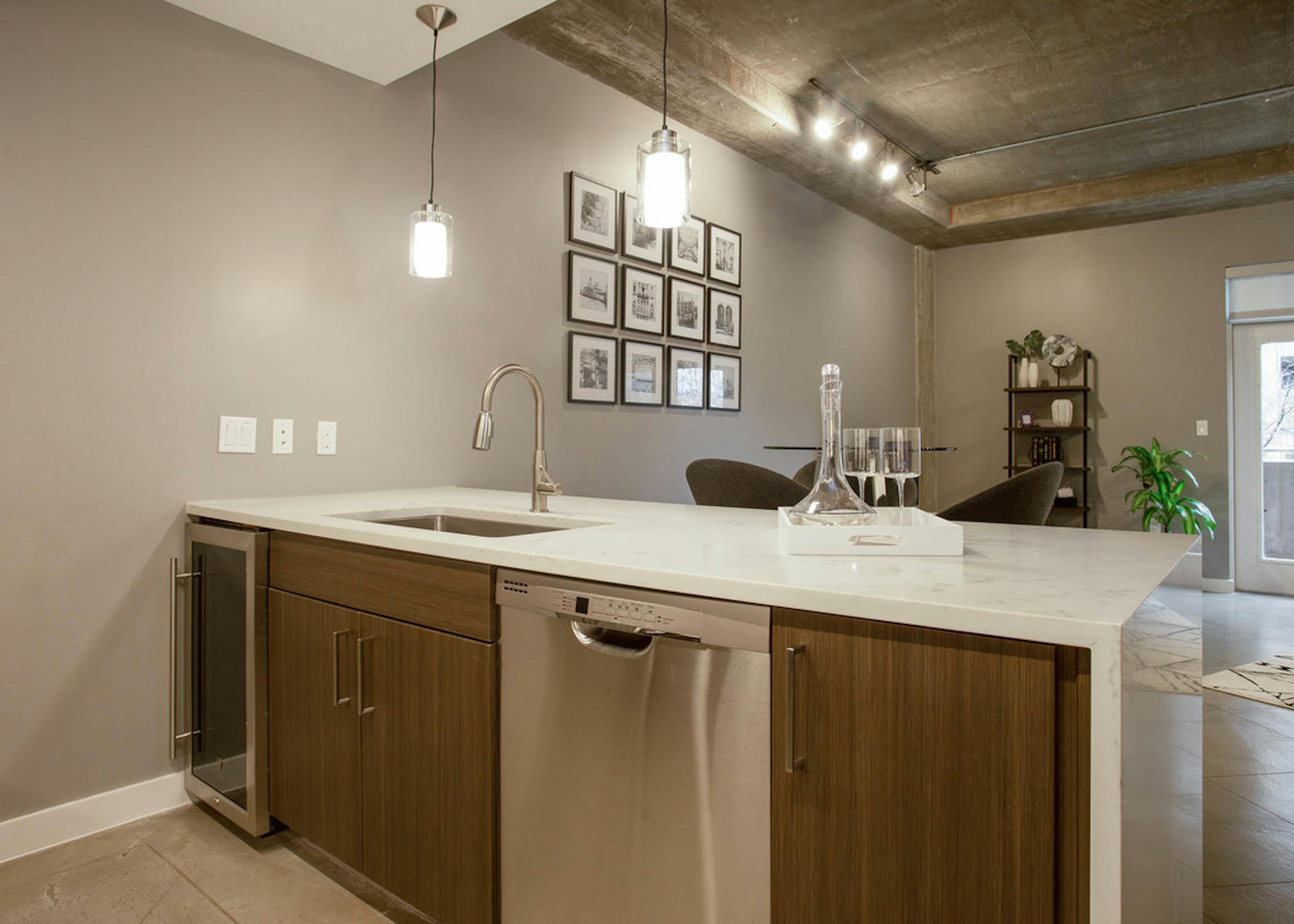View from behind AMLI Downtown kitchen island with peek into living area with natural light coming in through window