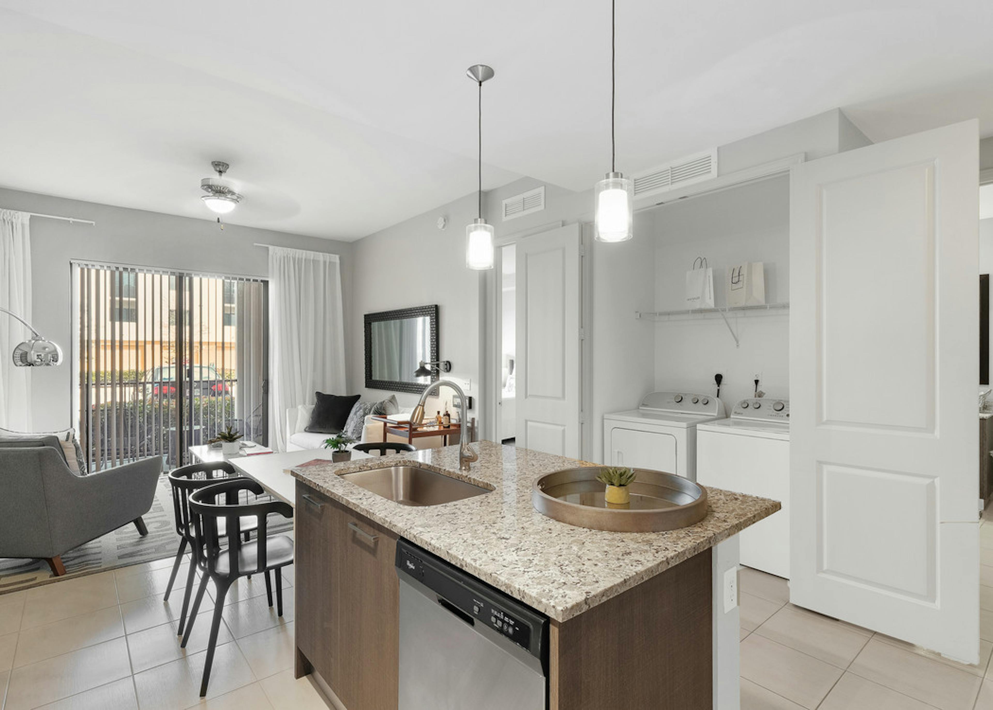 AMLI 8800 apartment with island kitchen with stools, stainless steel appliances, wood cabinetry and peek into living area 