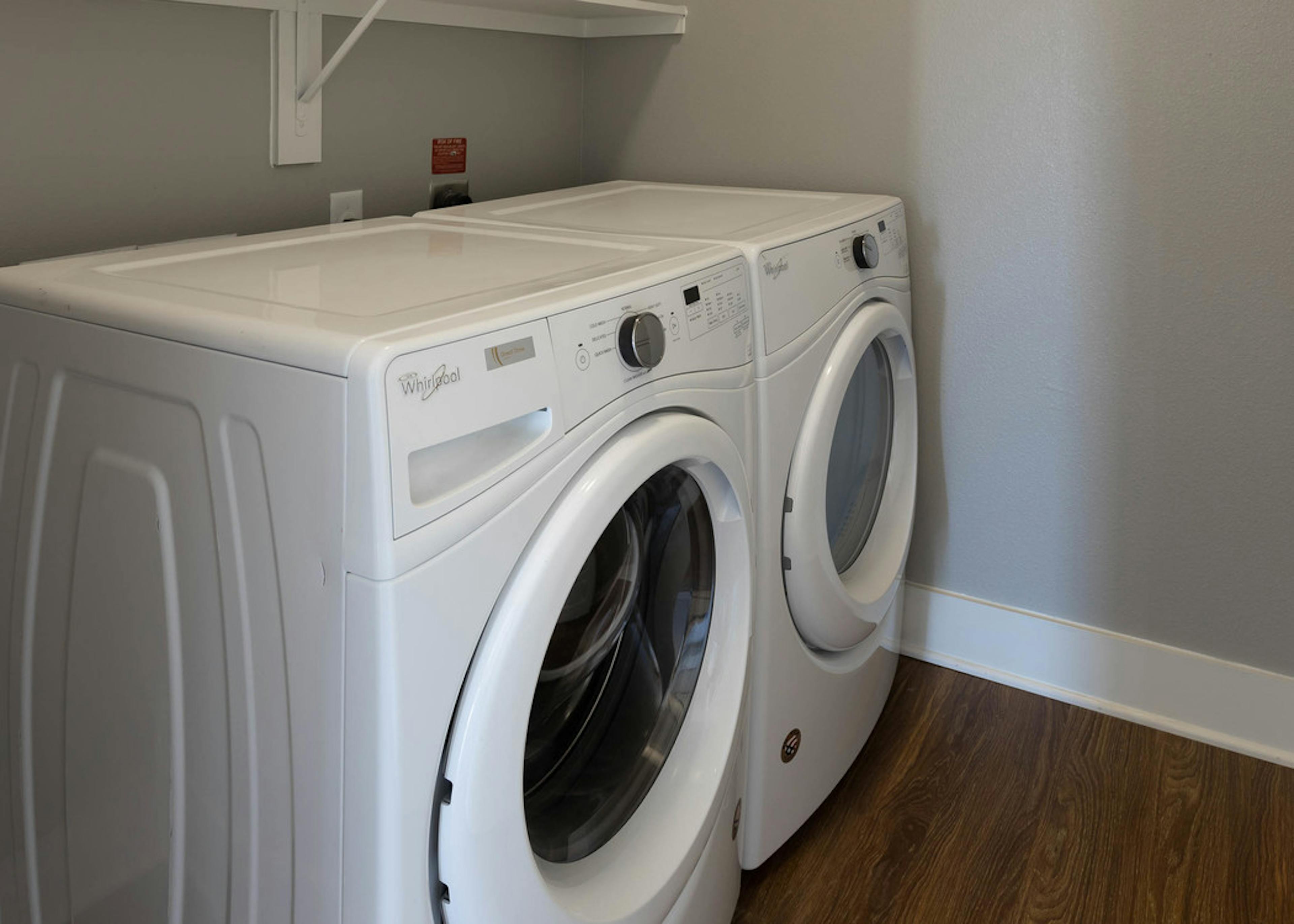 Close up view of in unit white washer and dryer set at AMLI on Aldrich apartment community with white trim and light walls