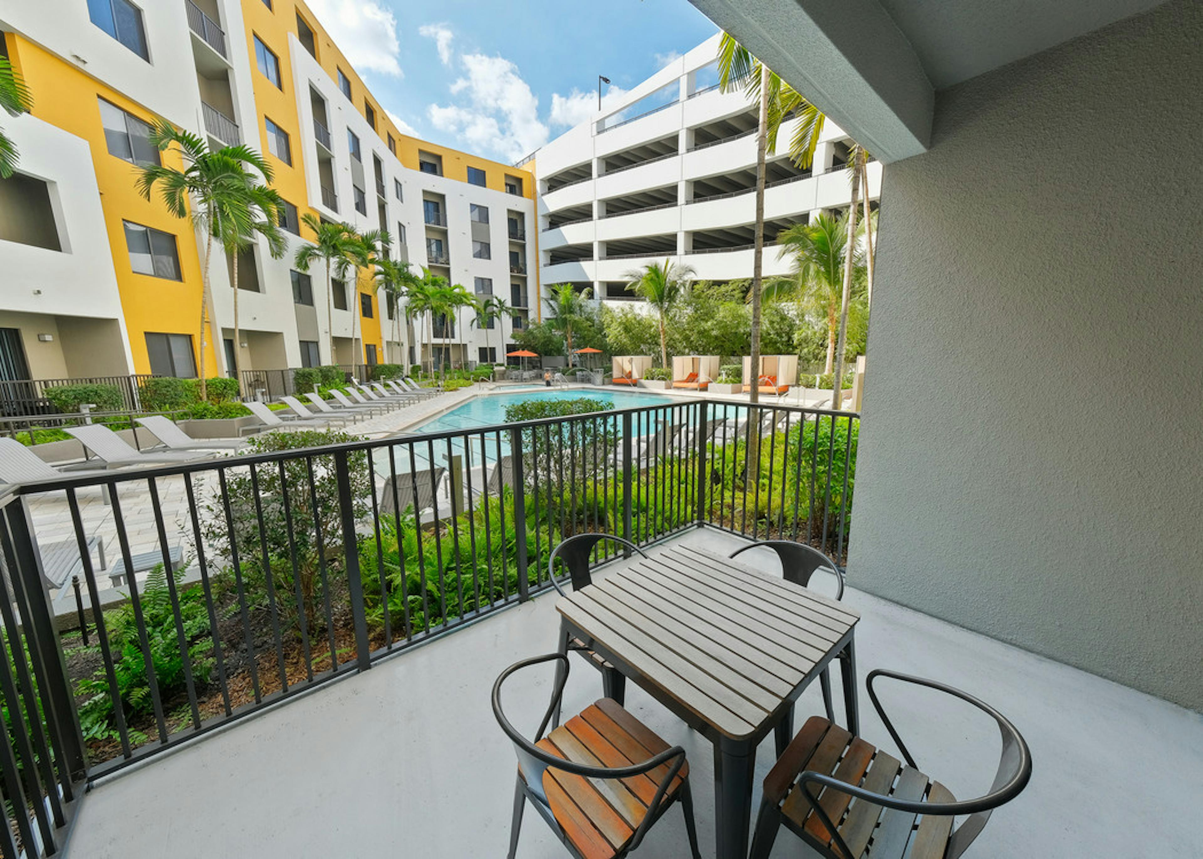Exterior daytime view of AMLI 8800 apartment private patio with table and chairs overlooking the pool