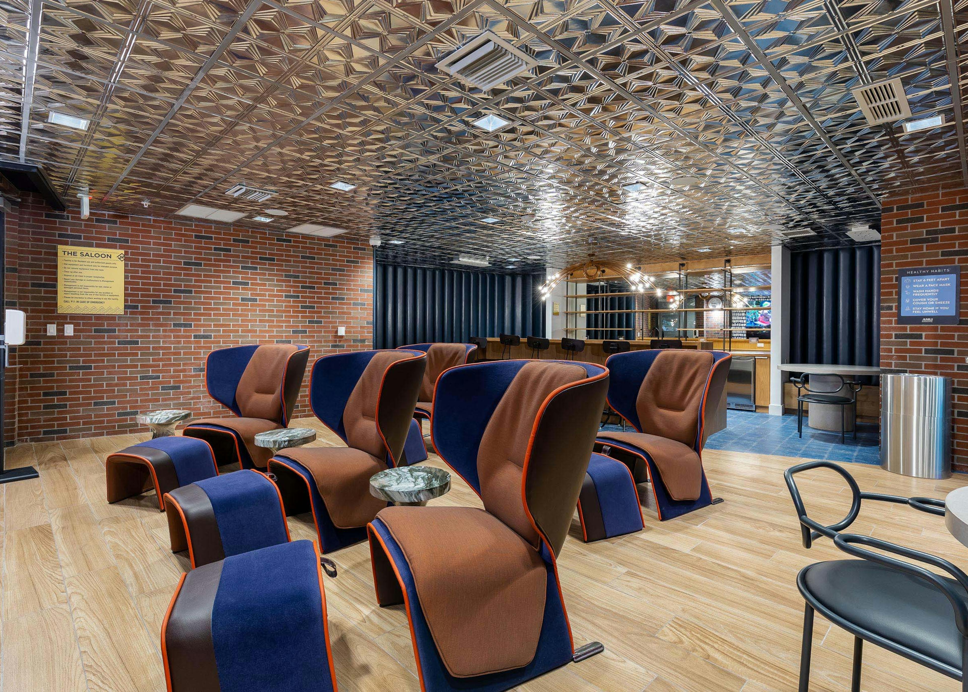 AMLI Midtown Miami theater room with large brown chairs and ottomans and wood floor with brick walls and silver ceiling