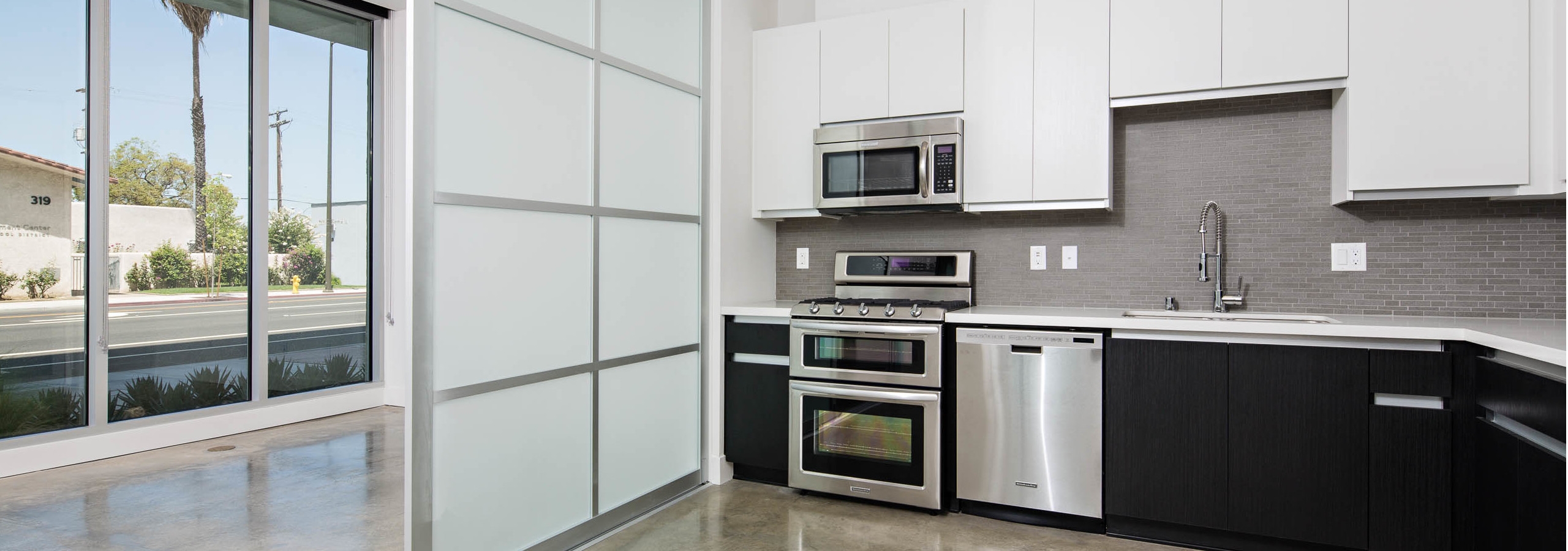 Interior of AMLI Lex on Orange apartment kitchen with quartz countertops, white cabinetry and frosted glass sliding door