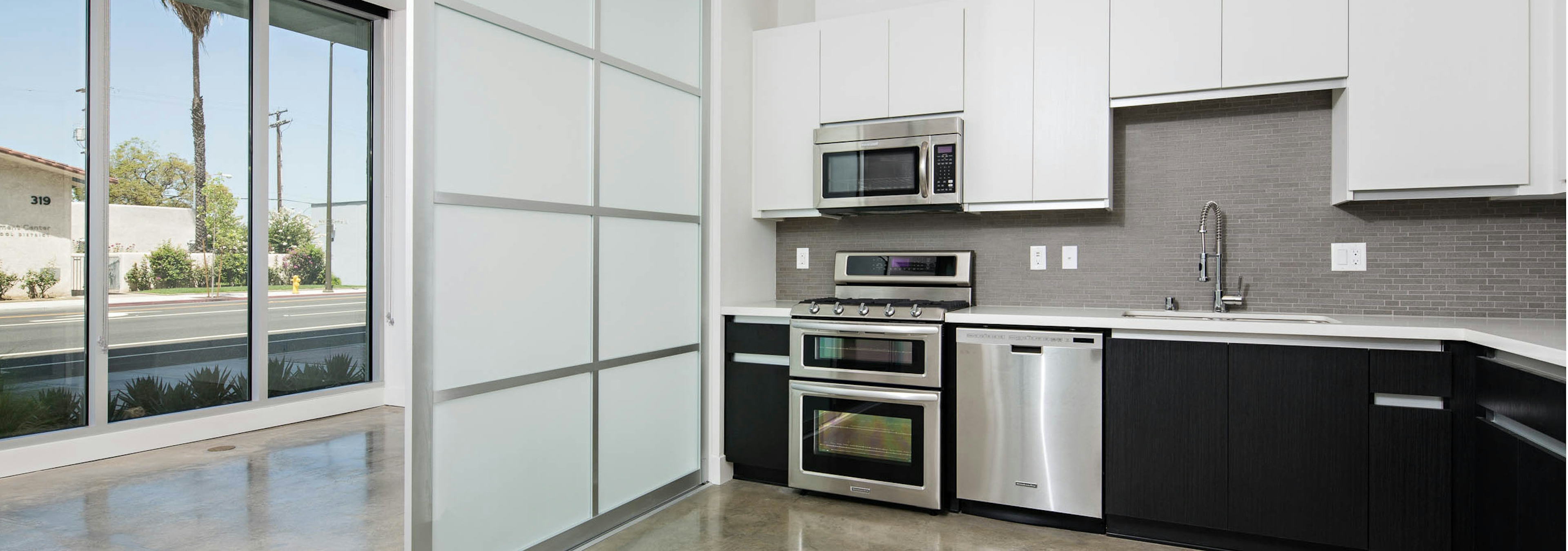 Interior of AMLI Lex on Orange apartment kitchen with quartz countertops, white cabinetry and frosted glass sliding door 