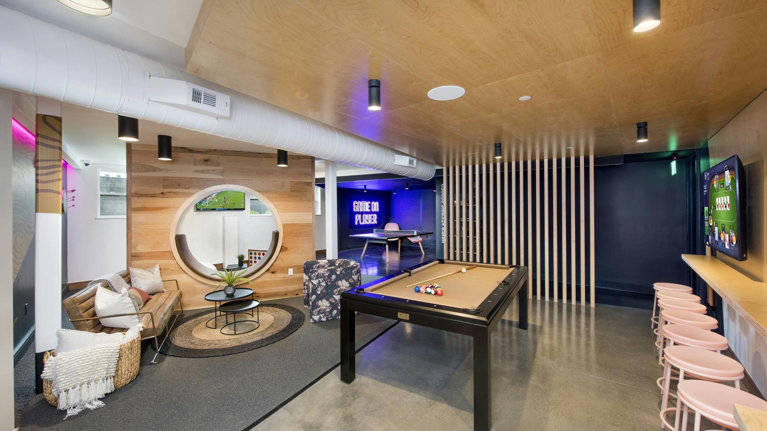 AMLI Lenox game room with pool table and ping pong table and television with multiple seating areas and wooden walls