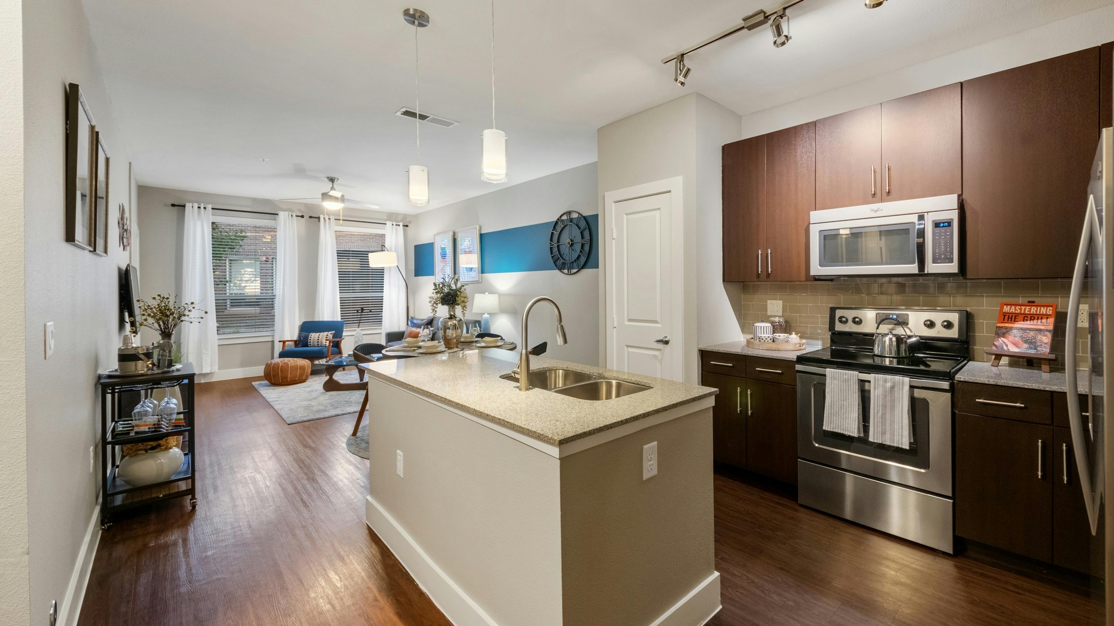 AMLI Riverfront Park apartment kitchen featuring a granite island and dark wood cabinetry with stainless steel appliances