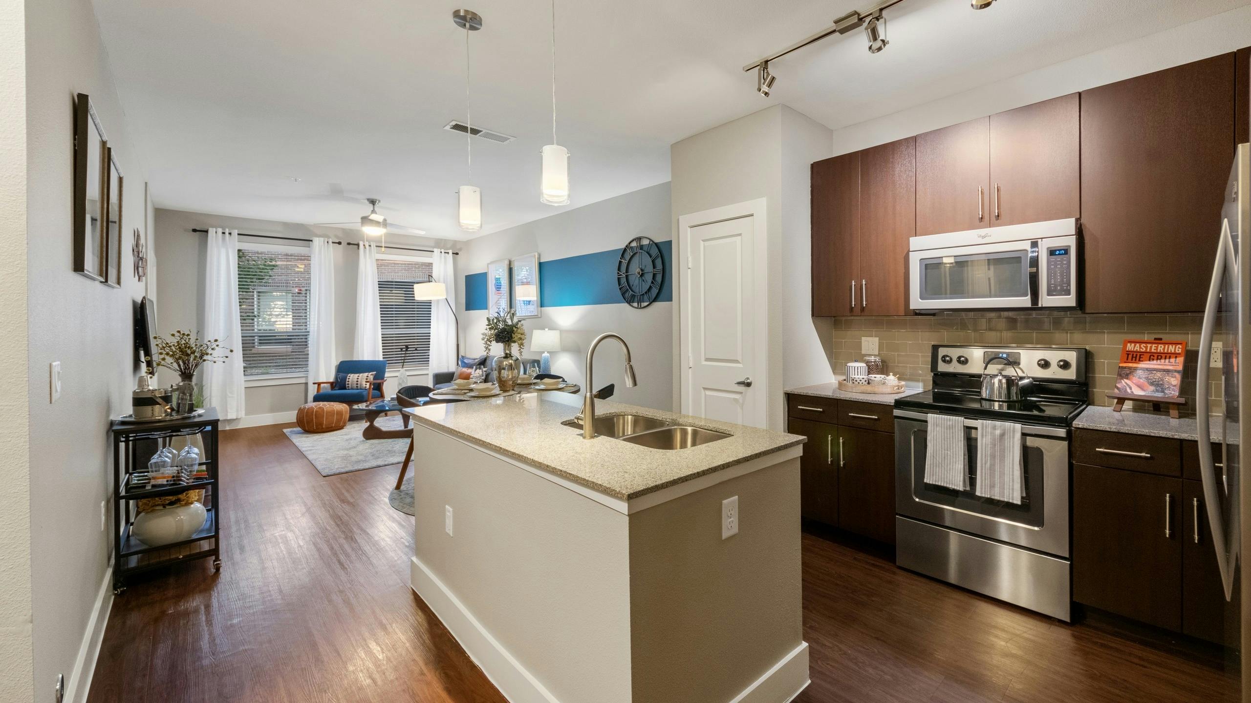AMLI Riverfront Park apartment kitchen featuring a granite island and dark wood cabinetry with stainless steel appliances