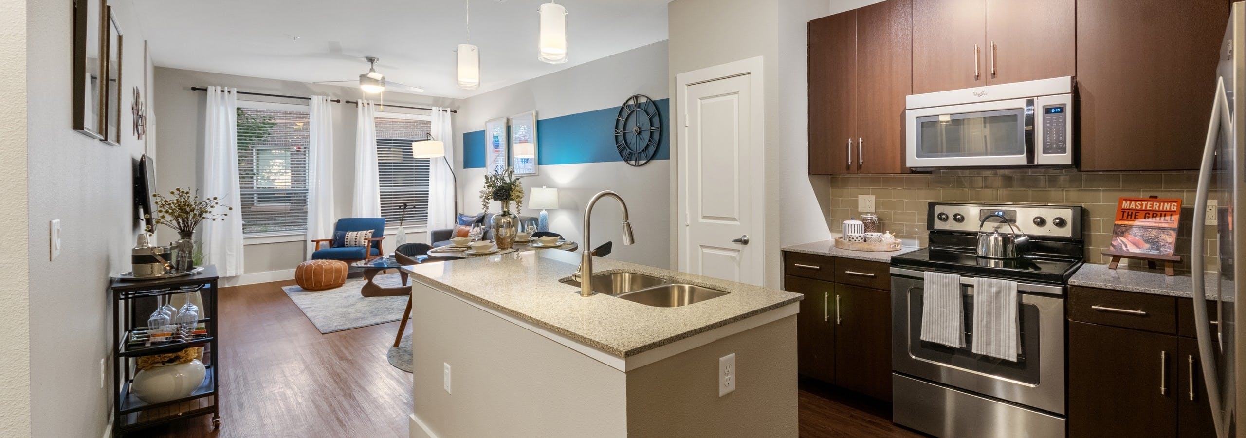 AMLI Riverfront Park apartment kitchen featuring a granite island and dark wood cabinetry with stainless steel appliances