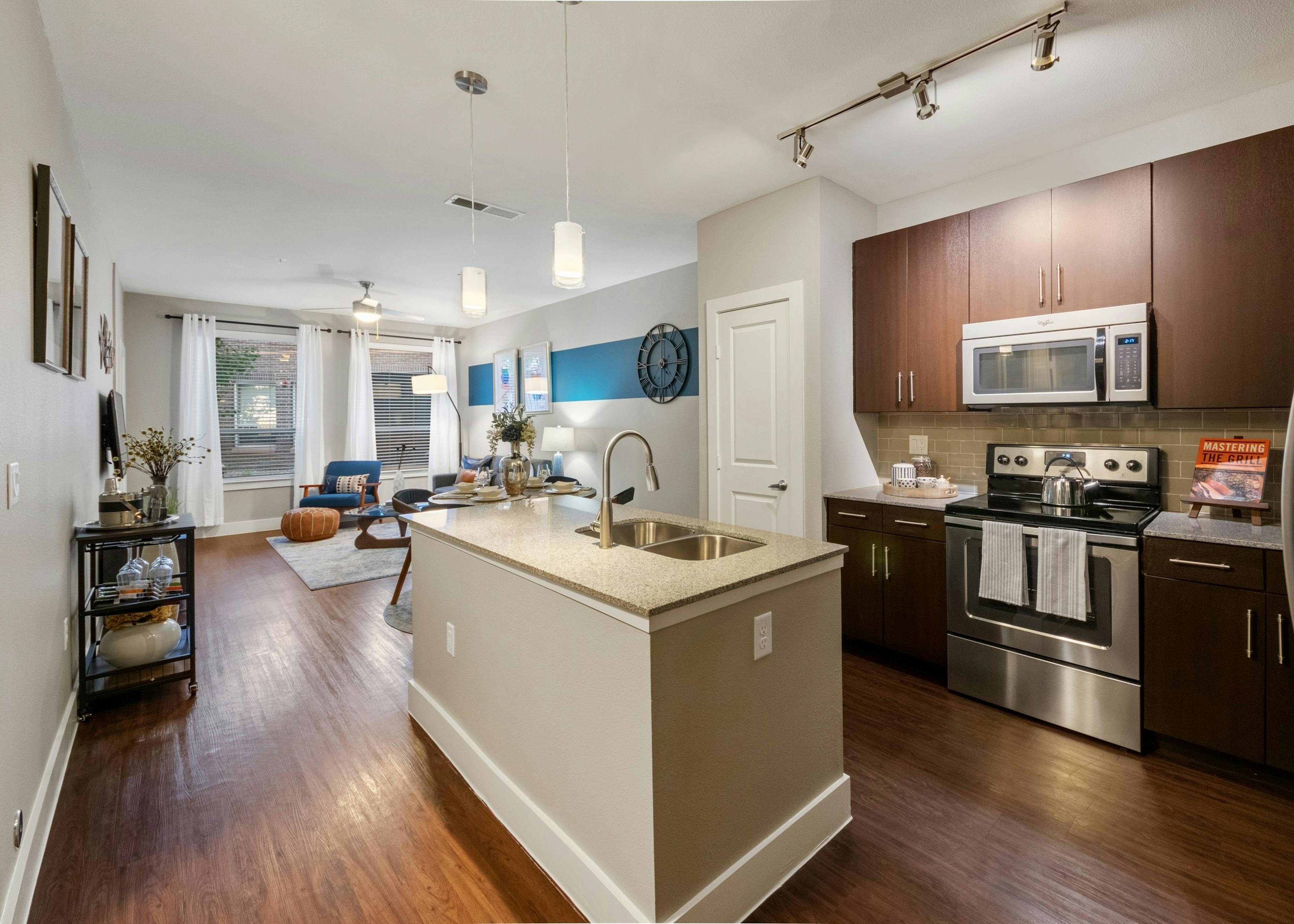 AMLI Riverfront Park apartment kitchen featuring a granite island and dark wood cabinetry with stainless steel appliances
