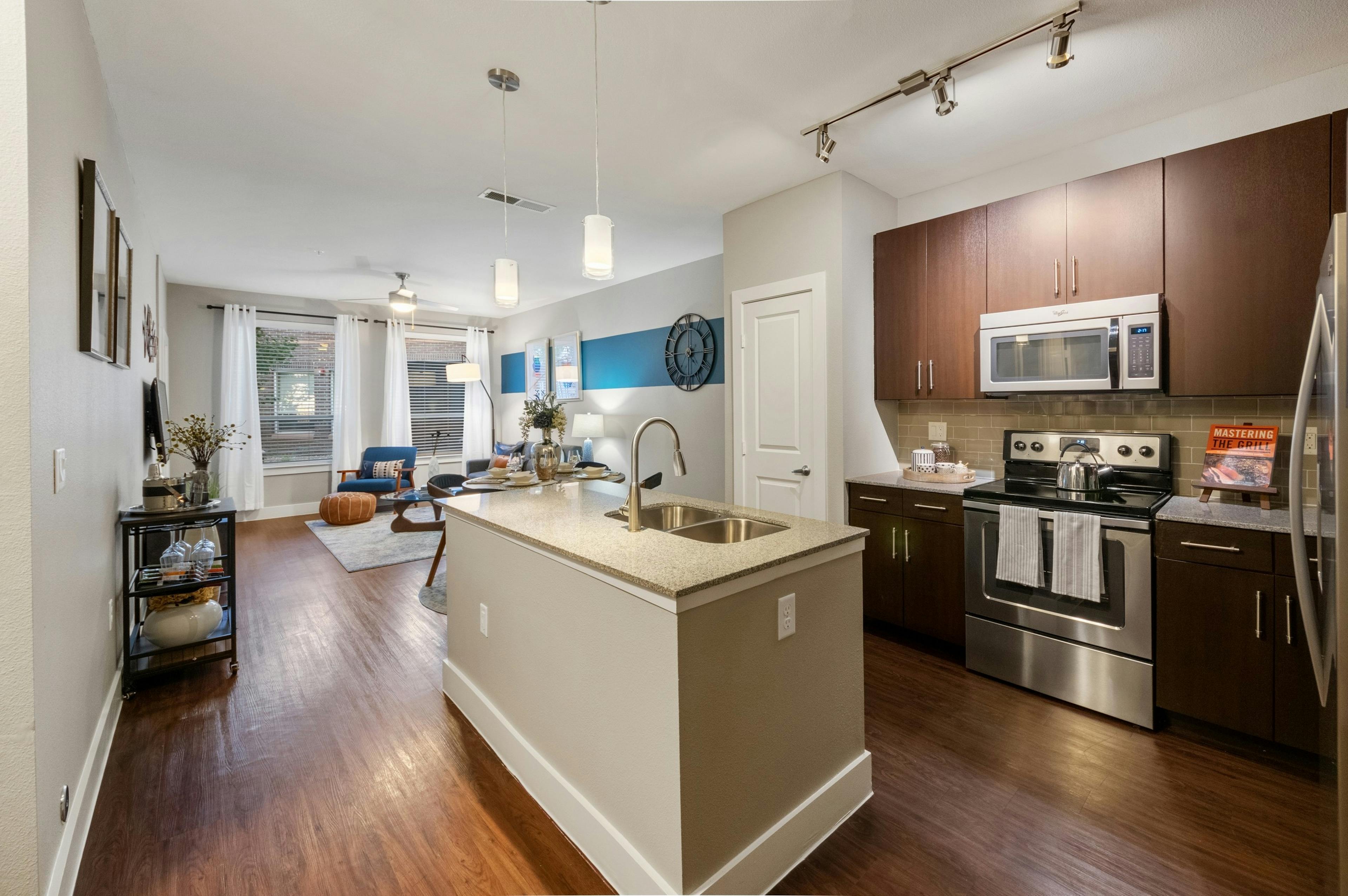 AMLI Riverfront Park apartment kitchen featuring a granite island and dark wood cabinetry with stainless steel appliances