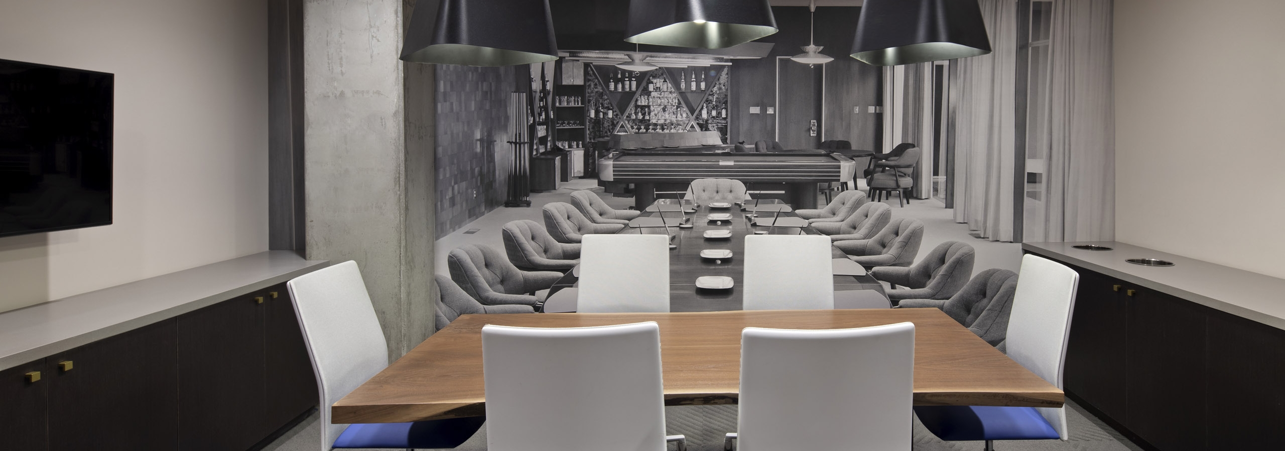 Interior view of conference room at AMLI Park Broadway apartments with table and six chairs and designer wallpaper and big screen TV