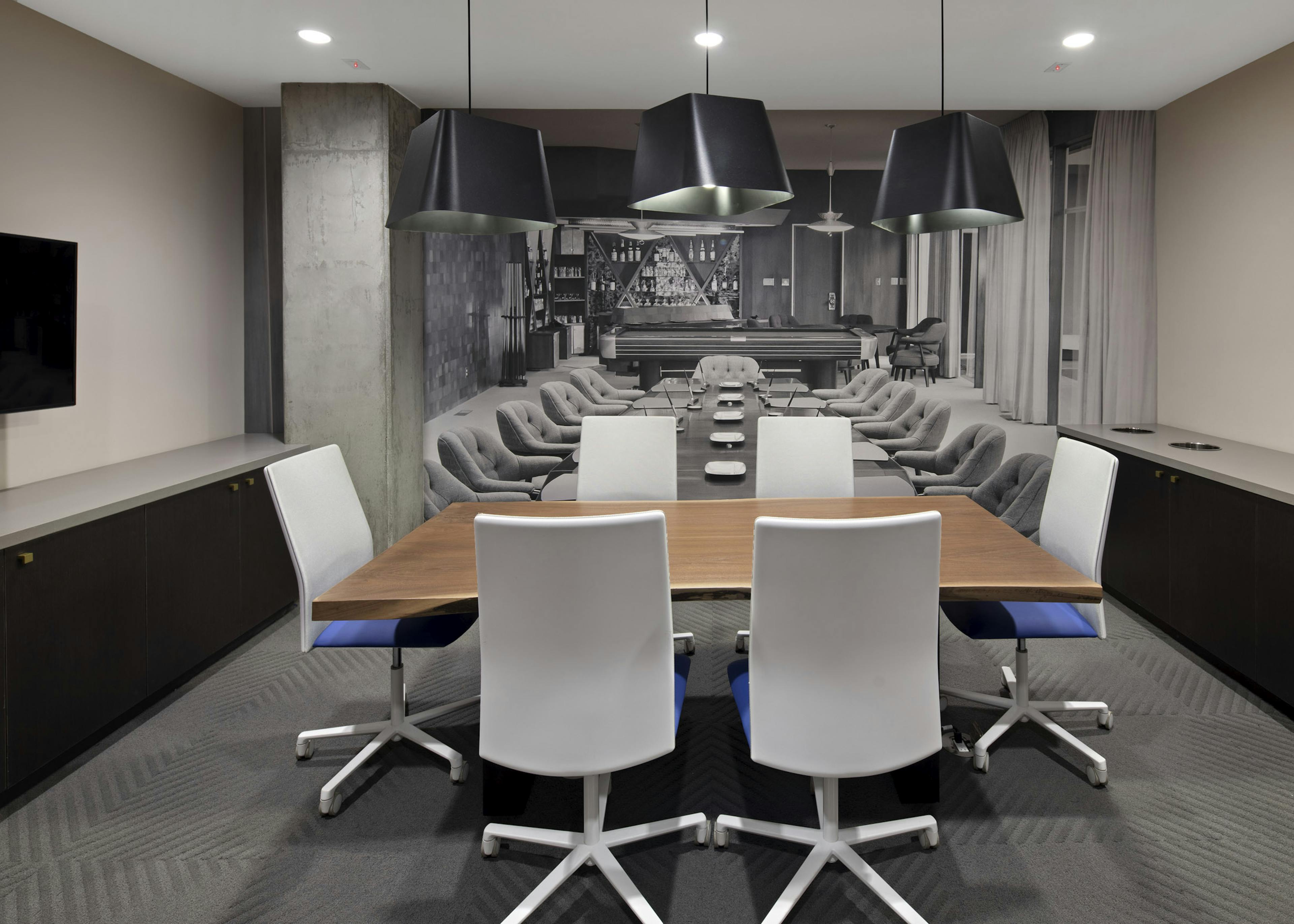 Interior view of conference room at AMLI Park Broadway apartments with table and six chairs and designer wallpaper and big screen TV
