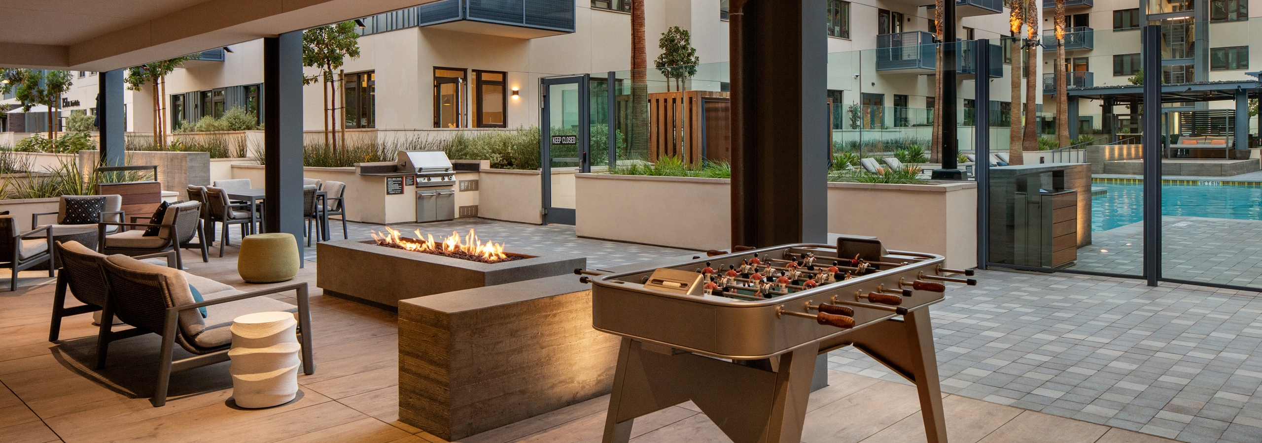 Dusk view of outdoor lounge sitting area with firepit and foosball facing the pool area at AMLI Old Pasadena apartments