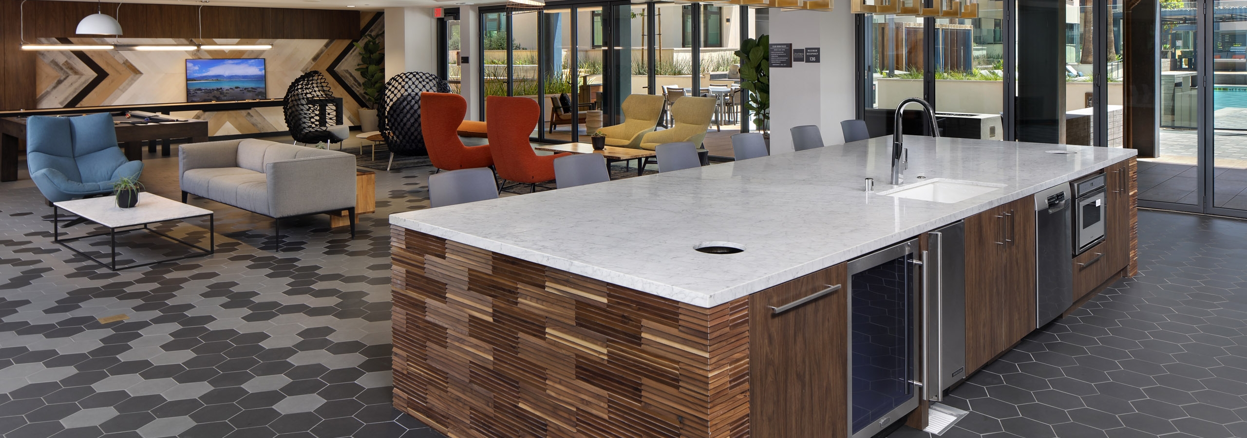 Clubroom kitchen island with side wood paneling detail and overhead decorative lighting at AMLI Old Pasadena apartments