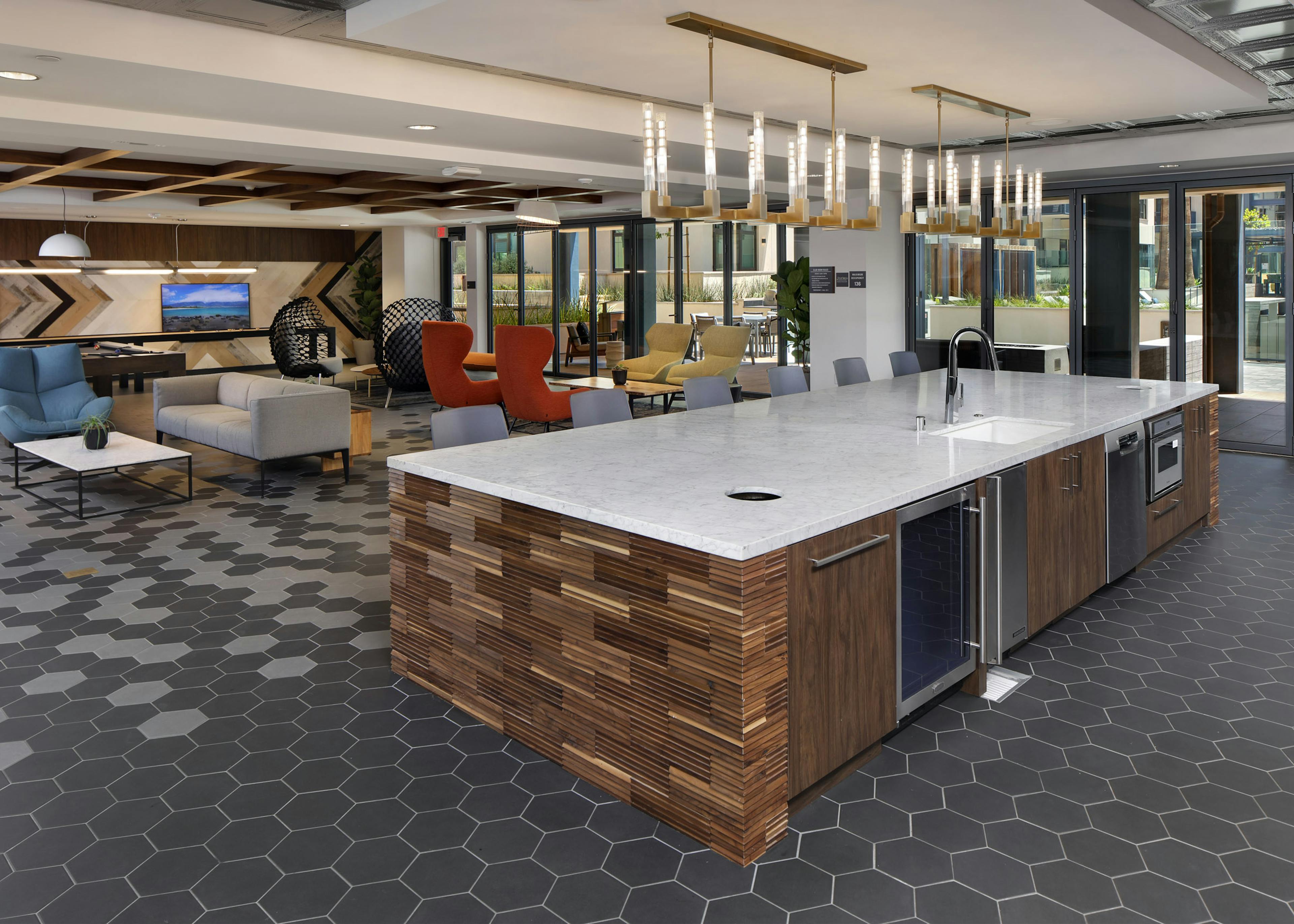 Clubroom kitchen island with side wood paneling detail and overhead decorative lighting at AMLI Old Pasadena apartments