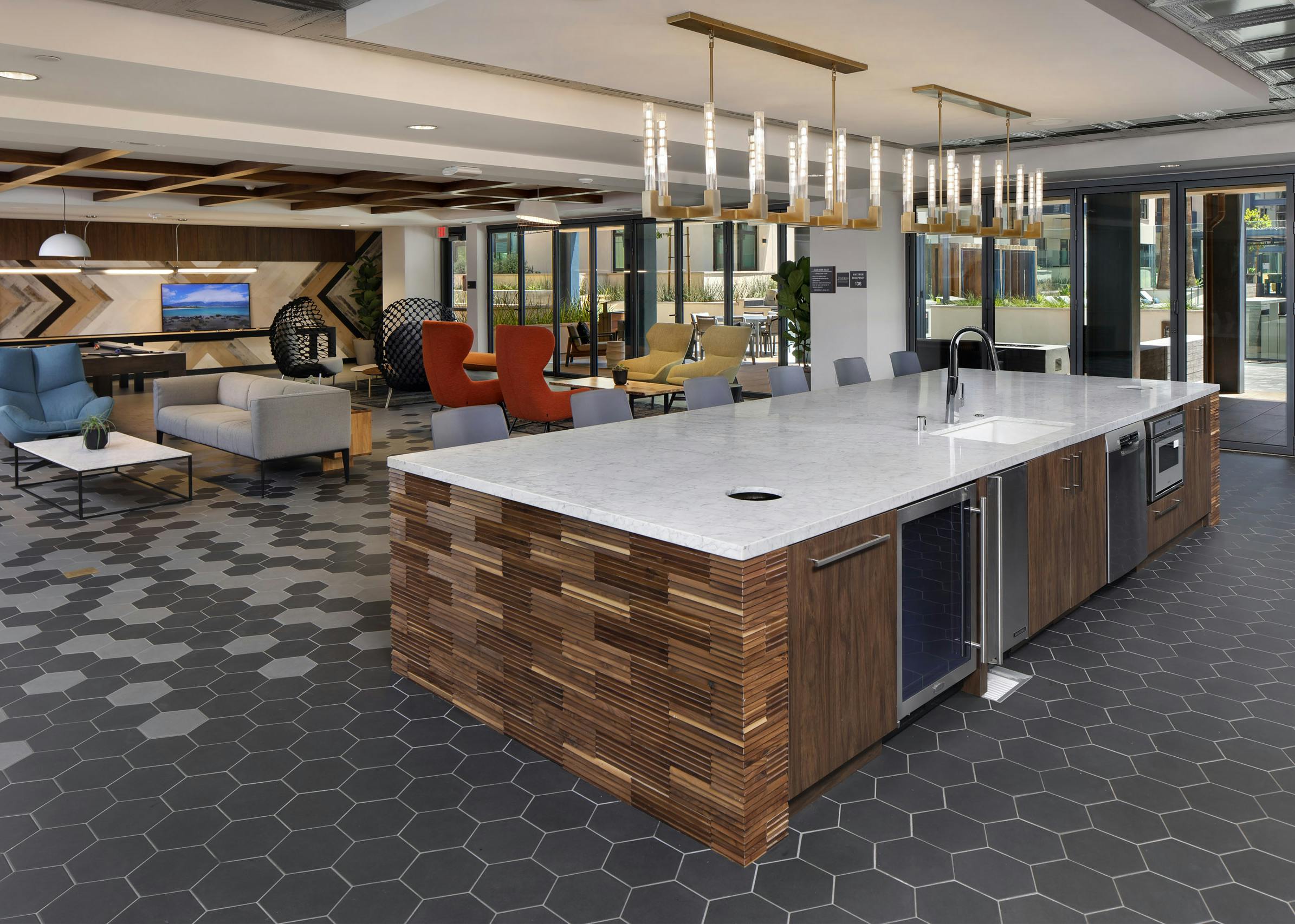 Clubroom kitchen island with side wood paneling detail and overhead decorative lighting at AMLI Old Pasadena apartments