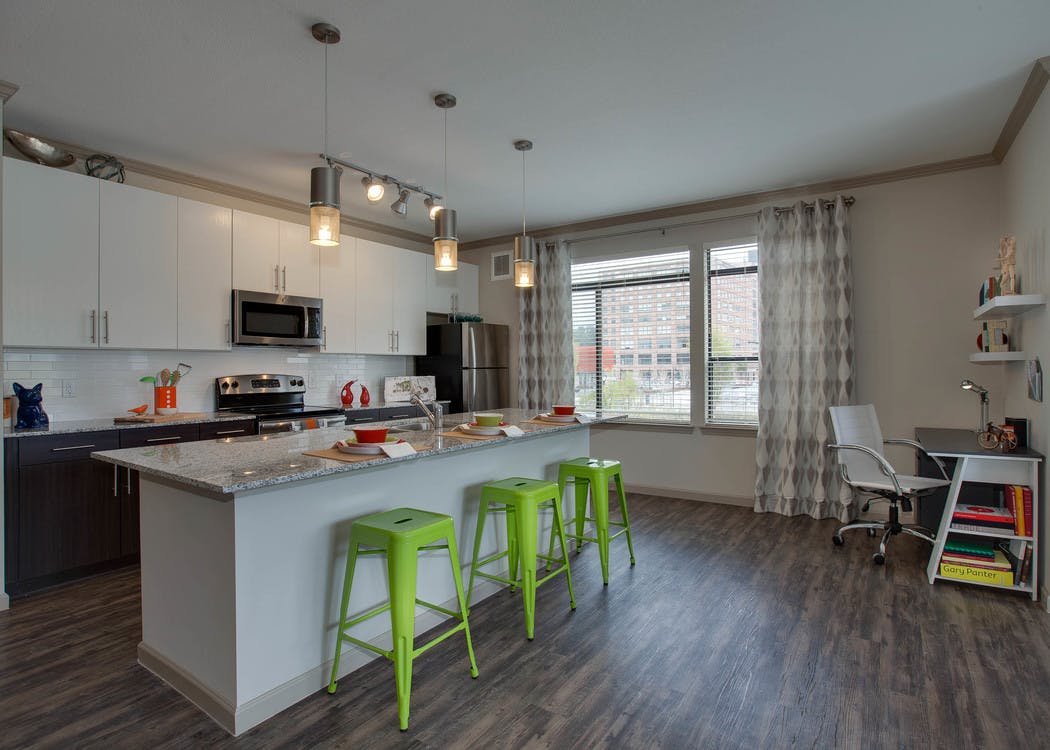 Interior view of AMLI Ponce Park apartment island kitchen with stainless steel appliances and white wood cabinetry
