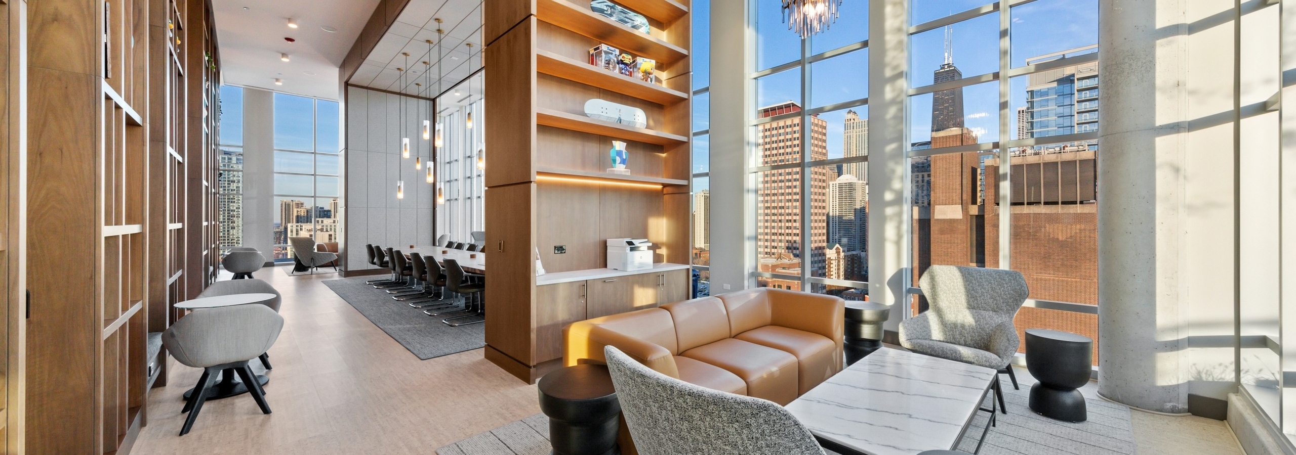 Modern seating area in AMLI 808 collab amenity space with tall wooden shelving and floor to ceiling windows with skyline view
