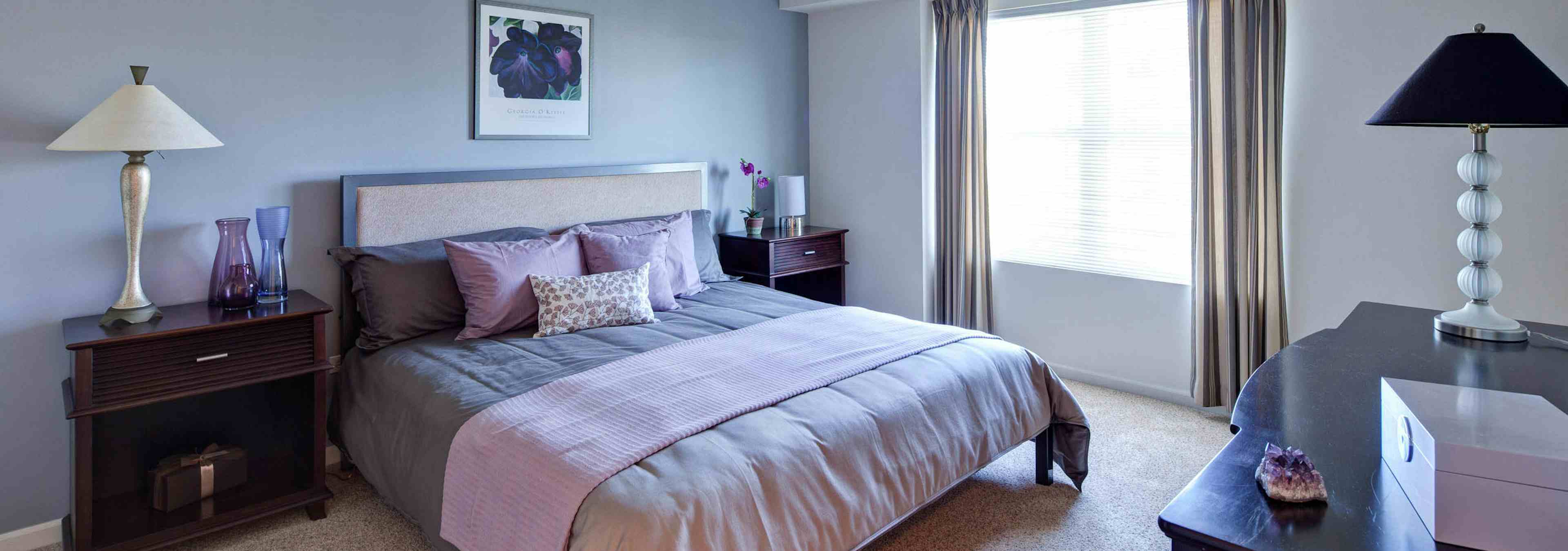 AMLI at Seven Bridges bedroom with grey decor and pink accents featuring a large bright window with flowing curtains