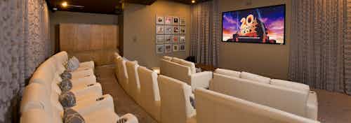 Interior view of AMLI RidgeGate media room with 3 rows of theater-style seating and centered wall mounted large flat screen