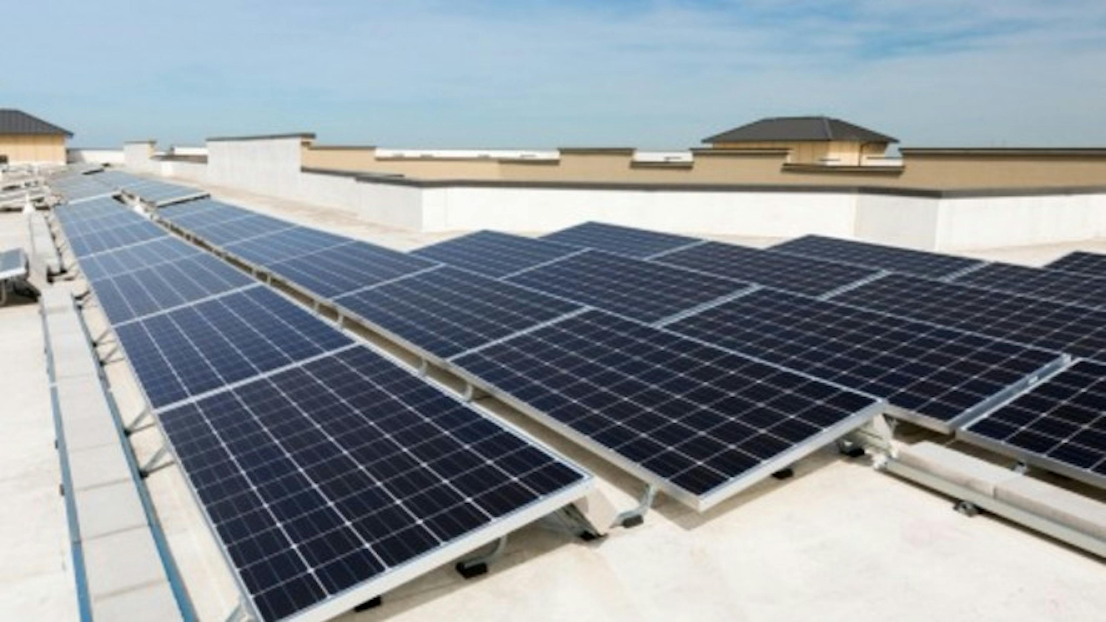 View of AMLI West Plano apartment community solar panel roofing promoting sustainability with blue sky in the background