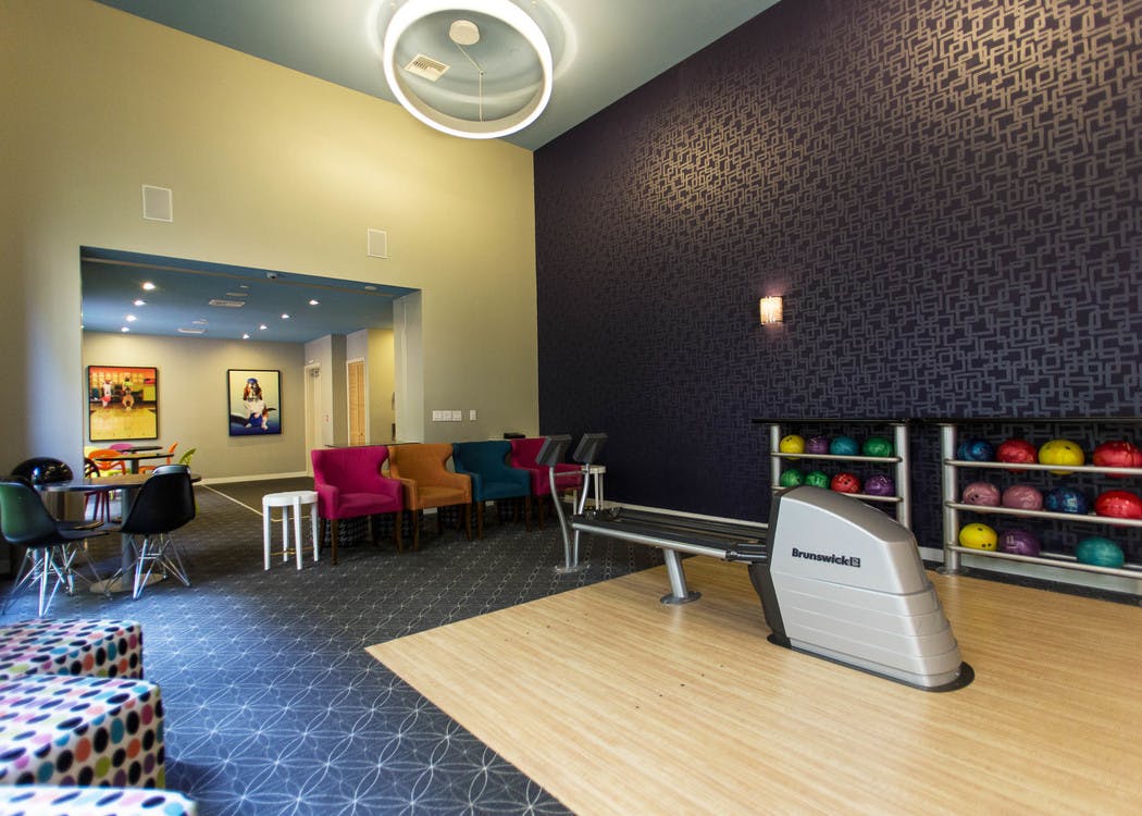 Interior of the two lane bowling alley at AMLI Dadeland apartment’s equipped with colorful bowling balls and tv screen