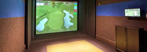 Indoor golf simulator amenity at AMLI Deerfield with simulated course image on large screen and smaller navigation screen