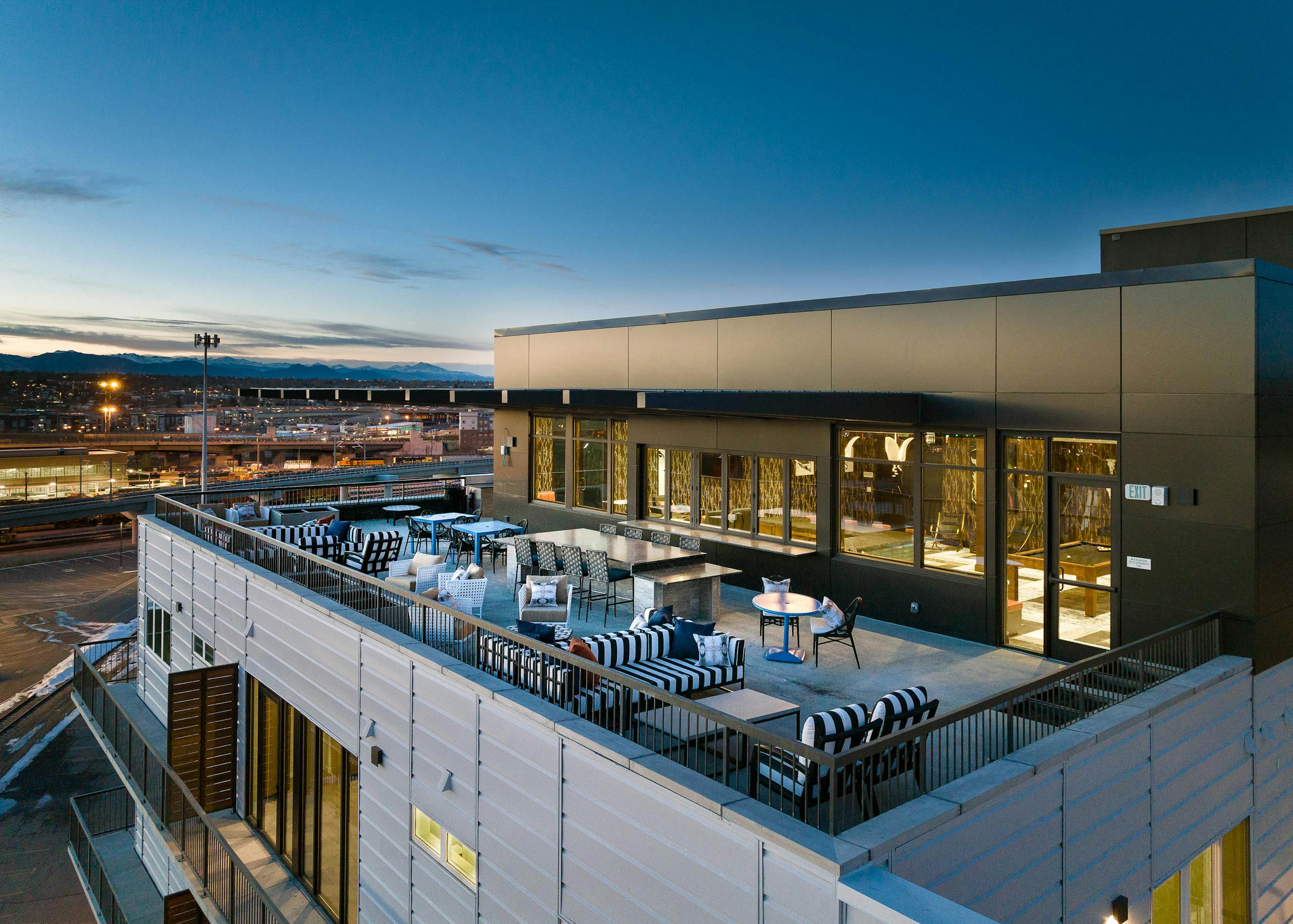 Aerial view of the sky lounge at AMLI Art District showcasing multiple couches and tables with chairs and view of mountains