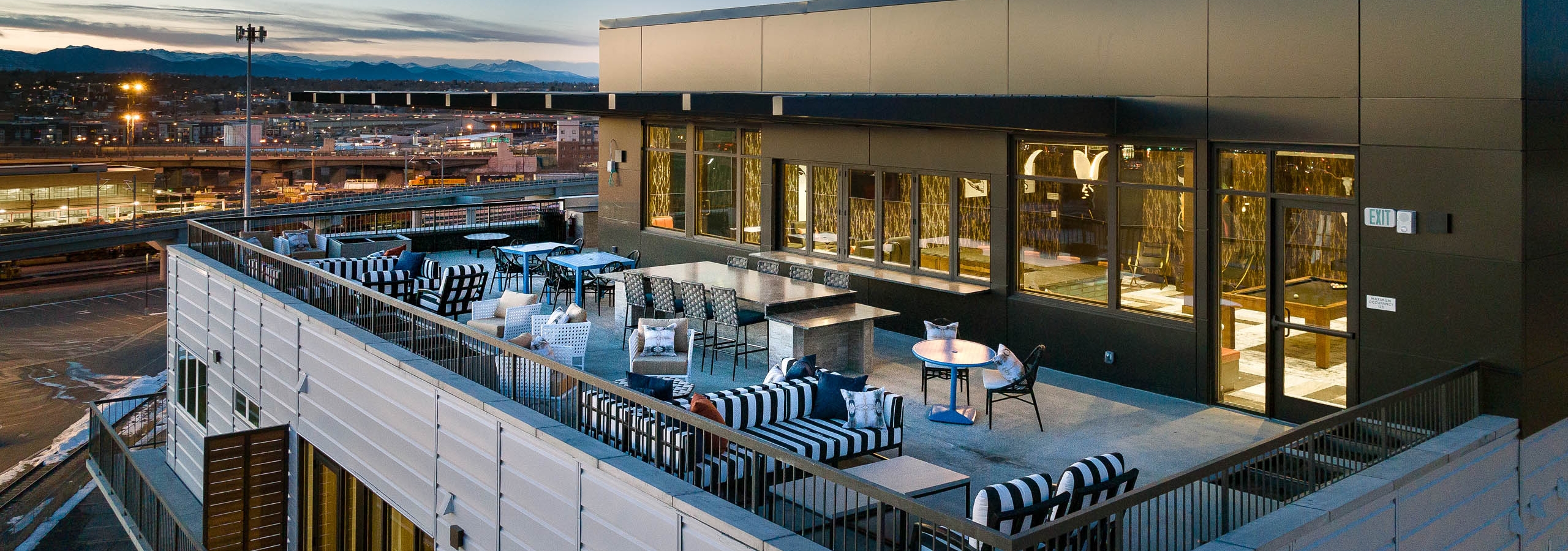 Aerial view of the sky lounge at AMLI Art District showcasing multiple couches and tables with chairs and view of mountains