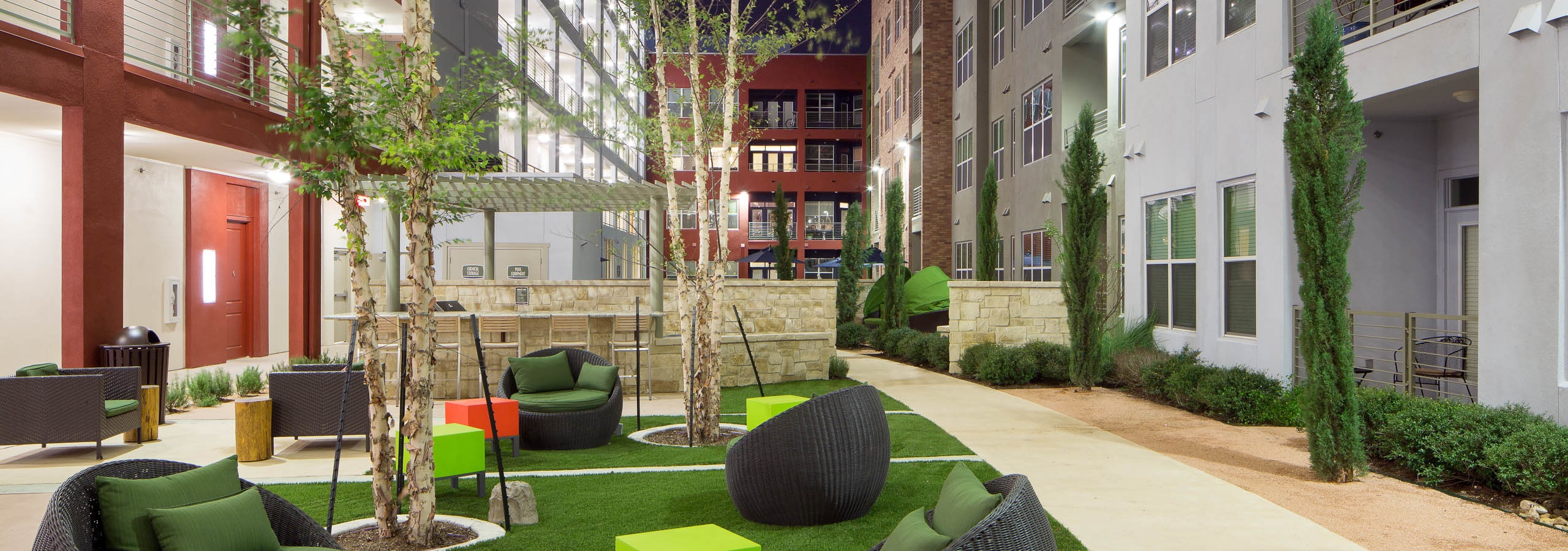 Courtyard at AMLI at Mueller with seating area on a grassy square in the center of surrounding pavement and shrubbery