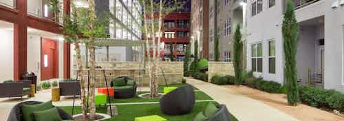 Courtyard at AMLI at Mueller with seating area on a grassy square in the center of surrounding pavement and shrubbery